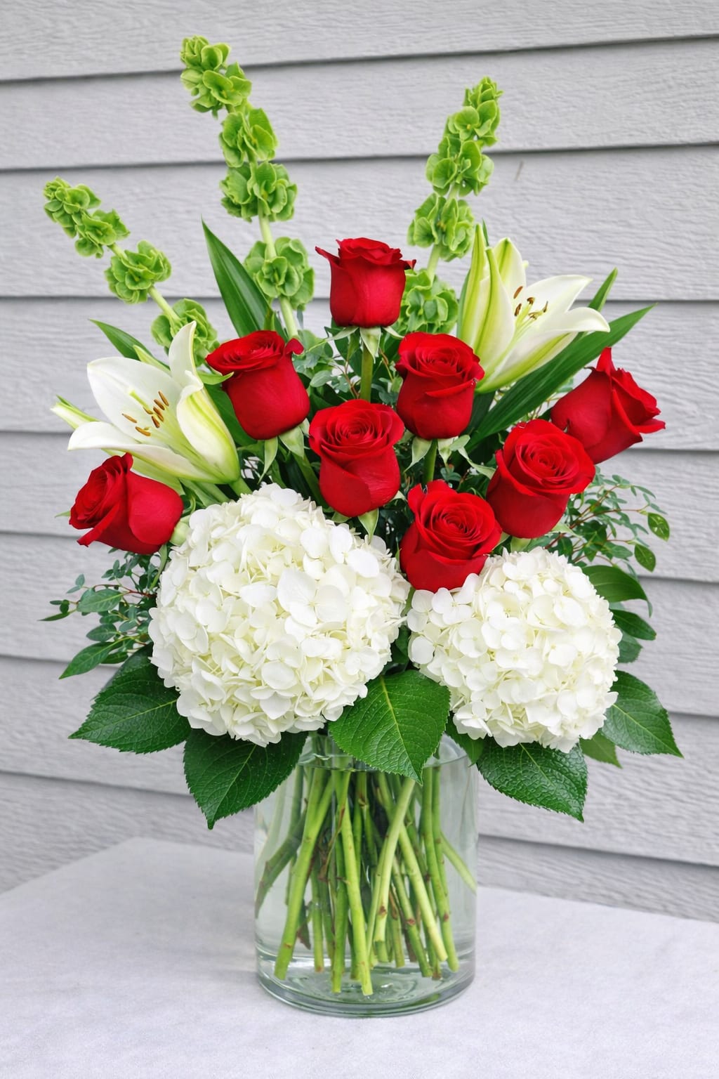 Red roses and white lilies with hydrangeas in a glass vase