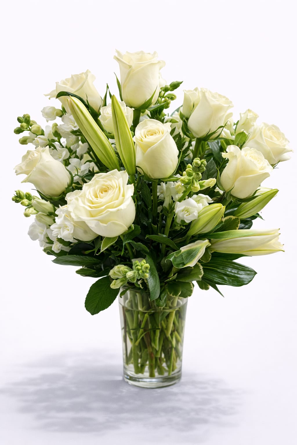 White roses and lilies arranged in a clear glass vase