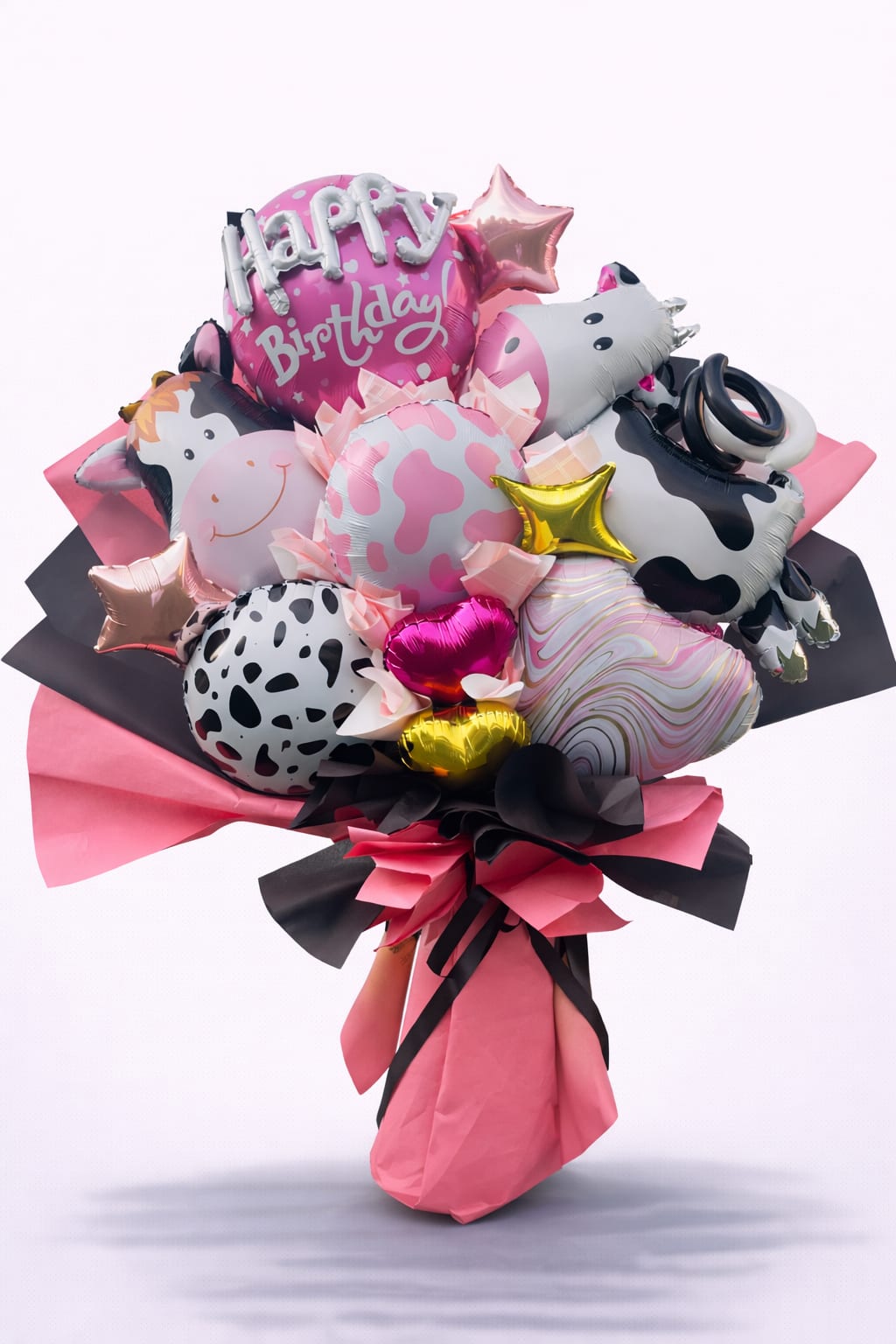 Birthday balloon bouquet with cow-print and pink foil balloons
