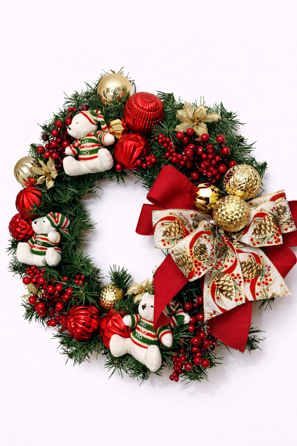 Decorative Christmas wreath with plush bears, red berries, red and gold ornaments, and a large red ribbon bow.