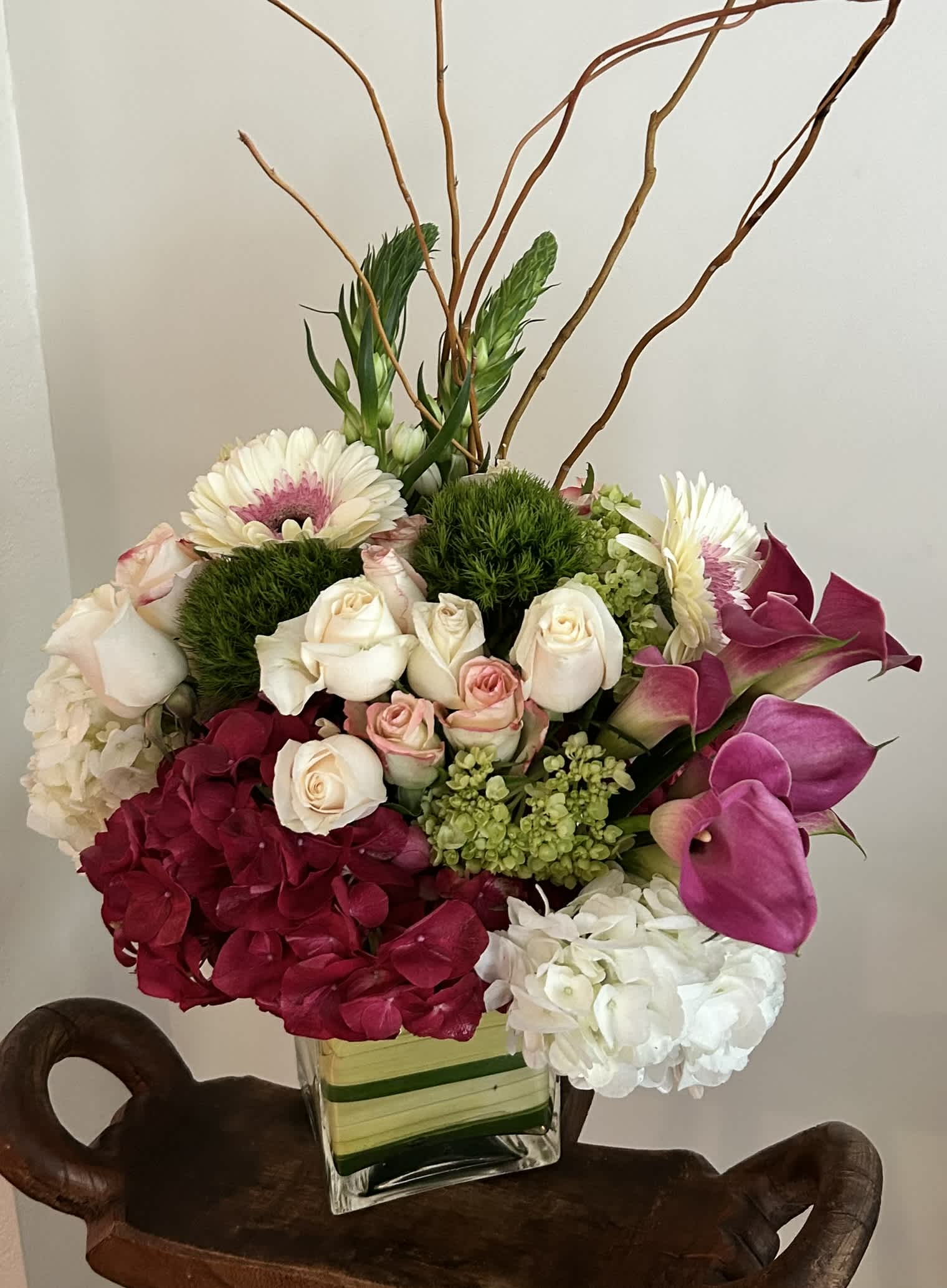 Mixed bouquet in a square glass vase with roses, hydrangea, gerbera daisies, and calla lilies