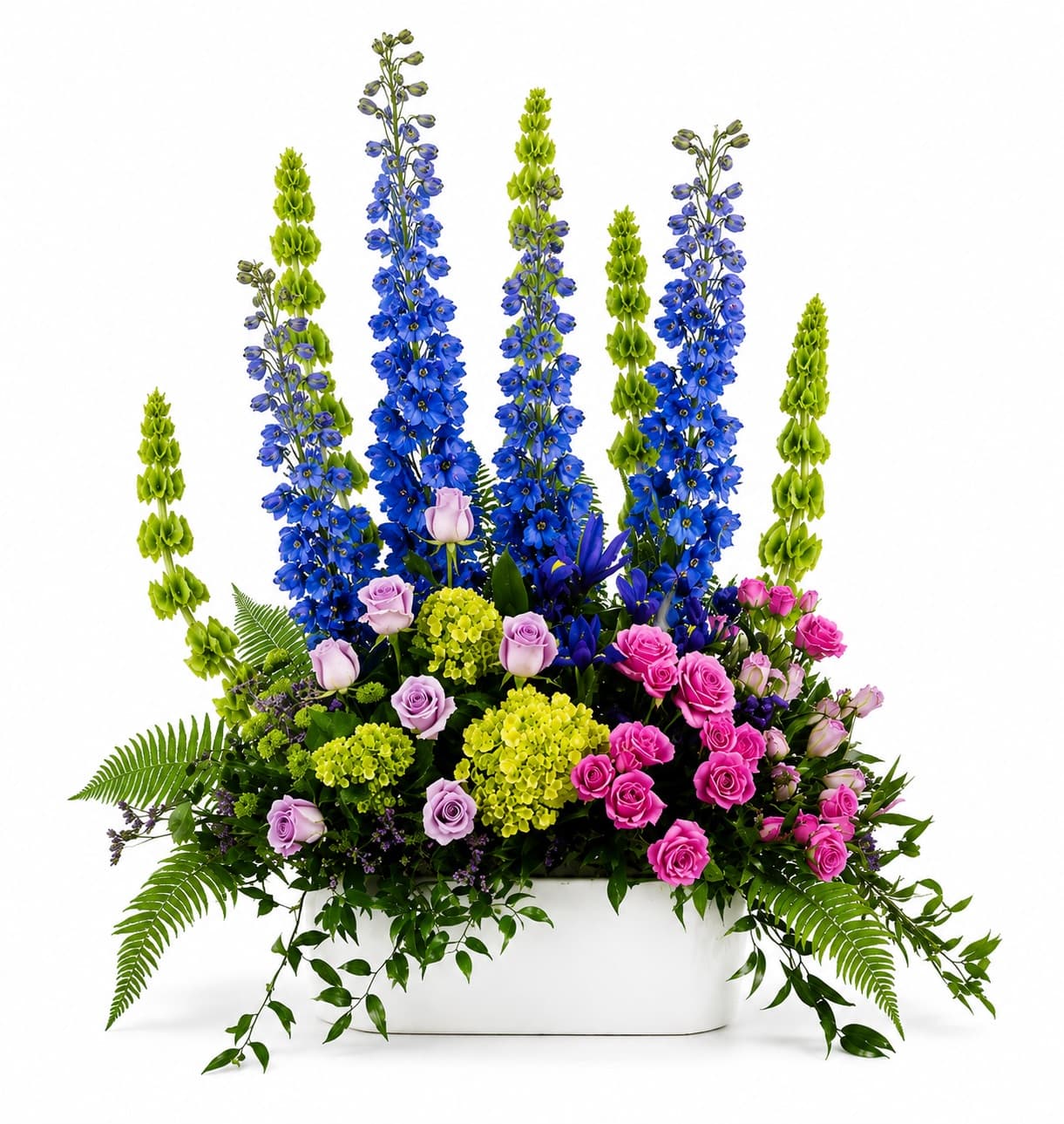 Tall floral arrangement with blue and green spikes and pink roses in a white container