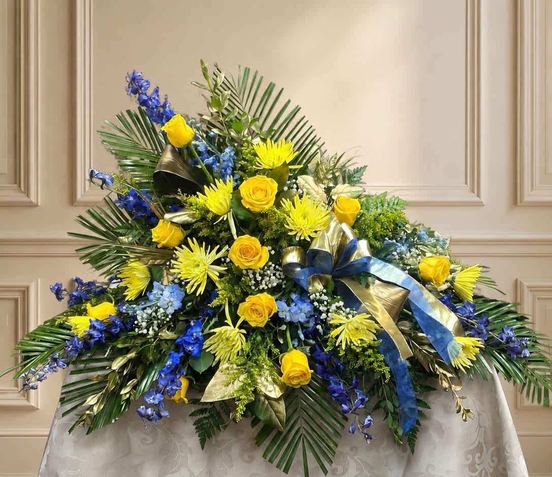 Large floral spray with yellow roses, blue flowers, and palm fronds