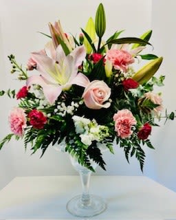 Pink lilies and roses arranged in a clear glass vase