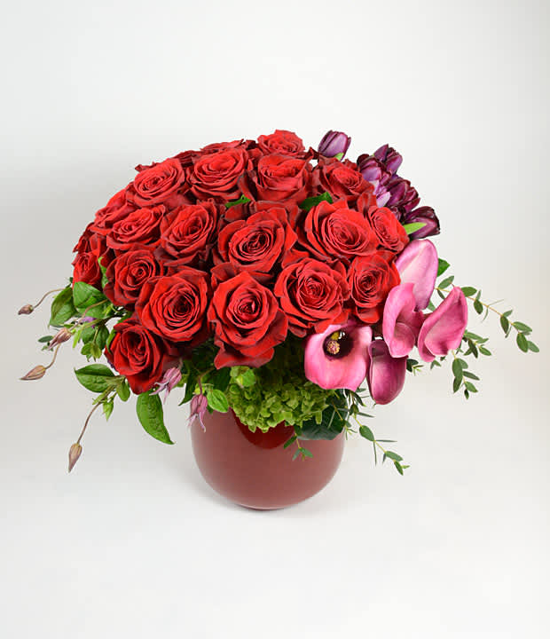 Love Knows No Bounds - Two dozen stunning red roses, vibrant tulips and elegant callas are accented with clematis and hydrangea and expertly designed and presented in our red glass vase. 