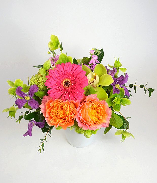 Bright mixed bouquet in a white vase with pink, orange, purple, and green blooms