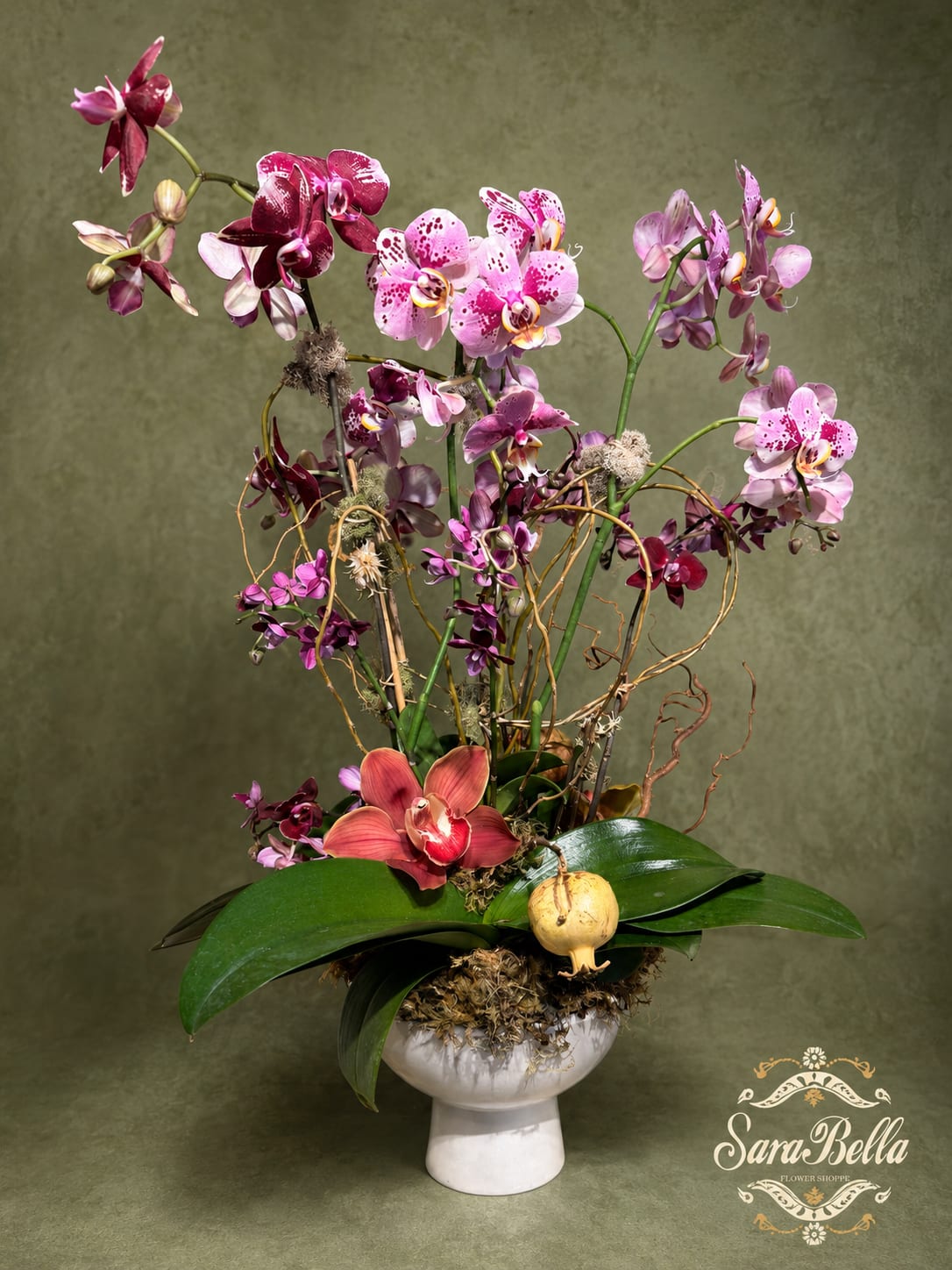 Tall orchid arrangement in a white pedestal vase with pink and purple blooms