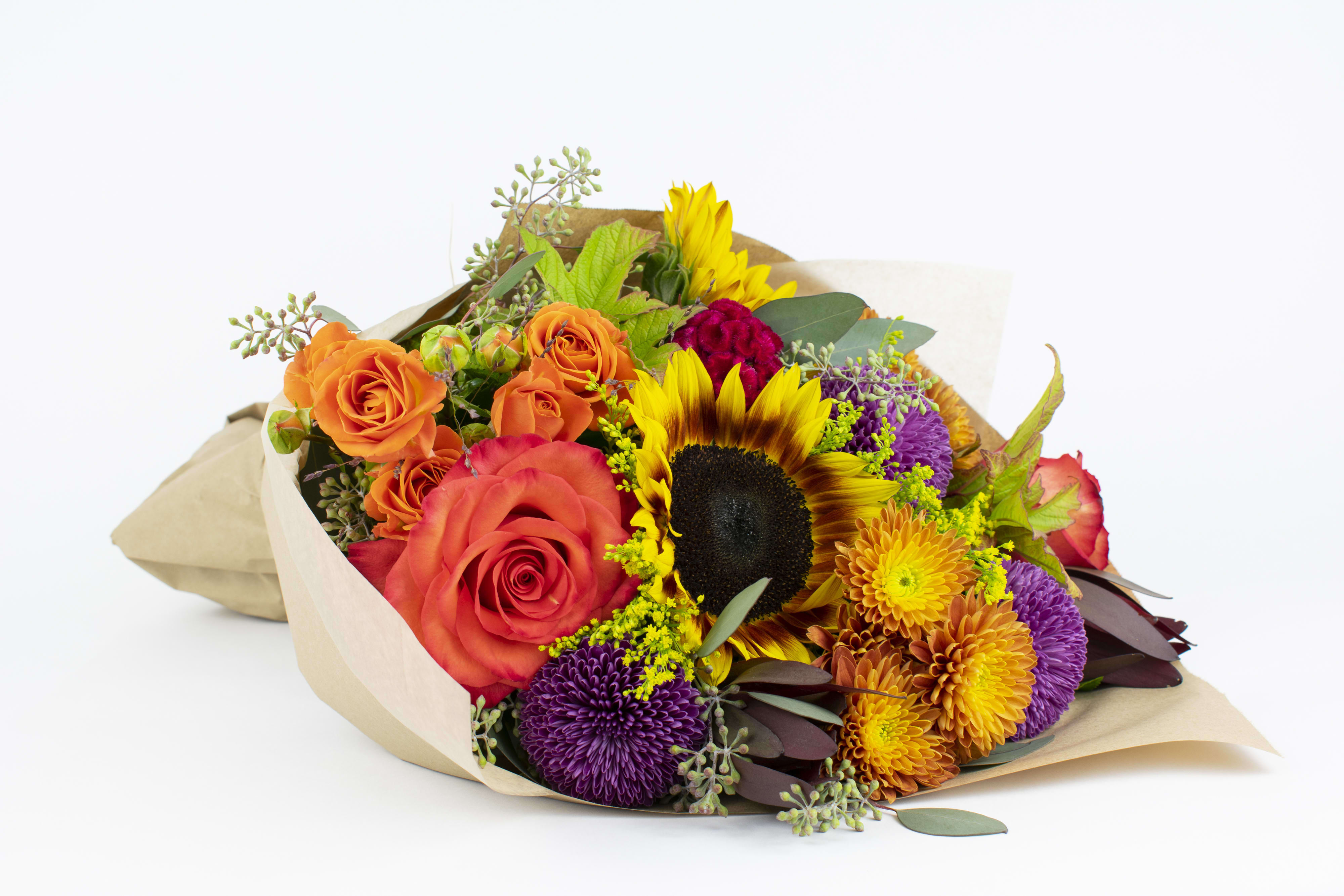 Bouquet of orange roses, sunflowers, and purple chrysanthemums wrapped in paper