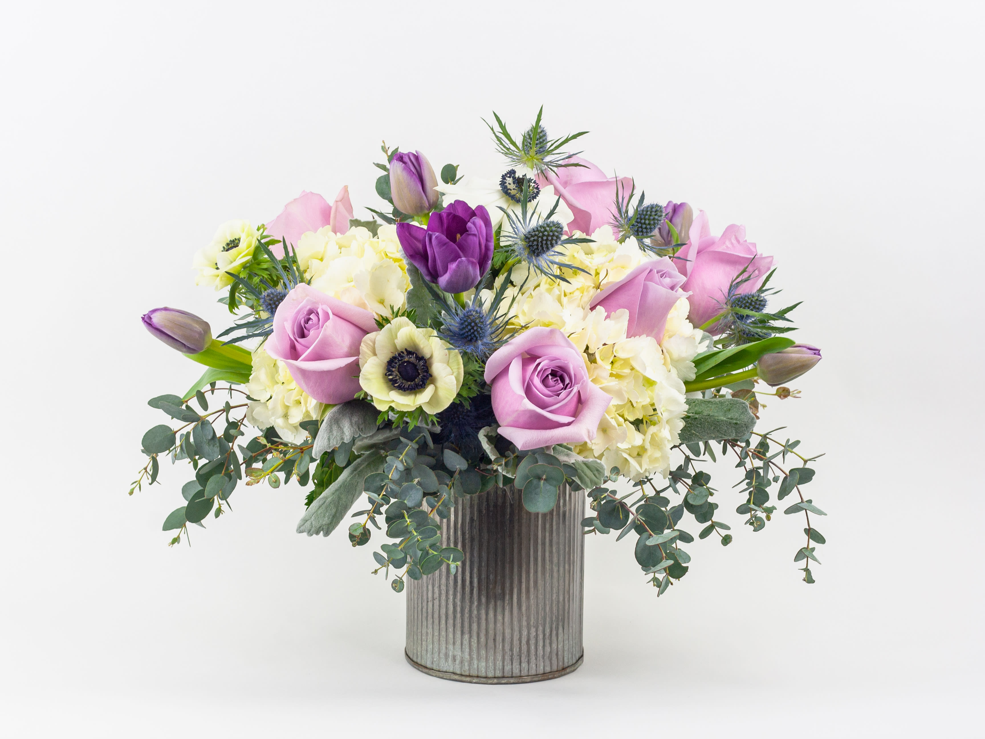 Lavender roses and purple tulips in a ribbed metal vase