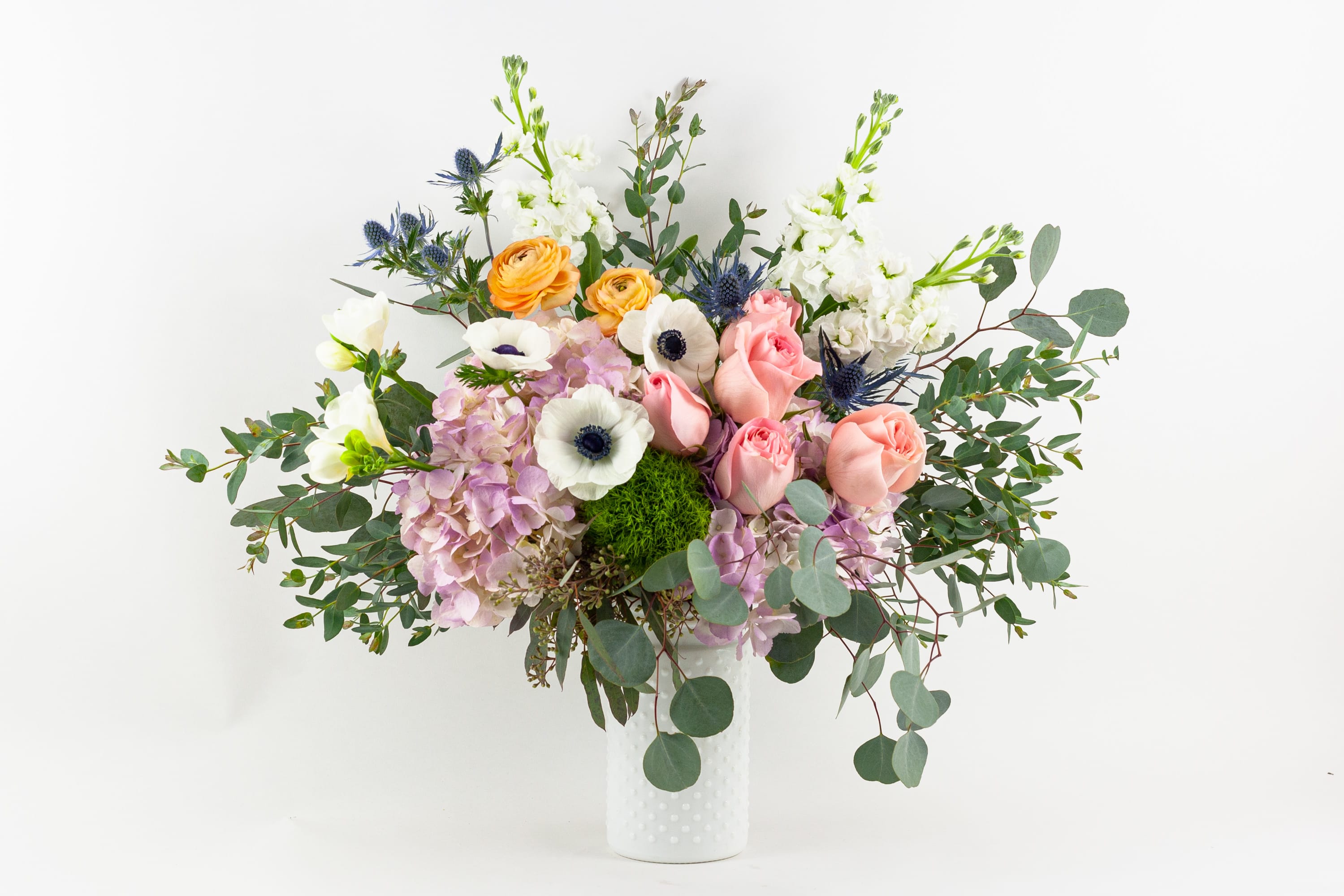 Mixed bouquet of pastel flowers in a white vase