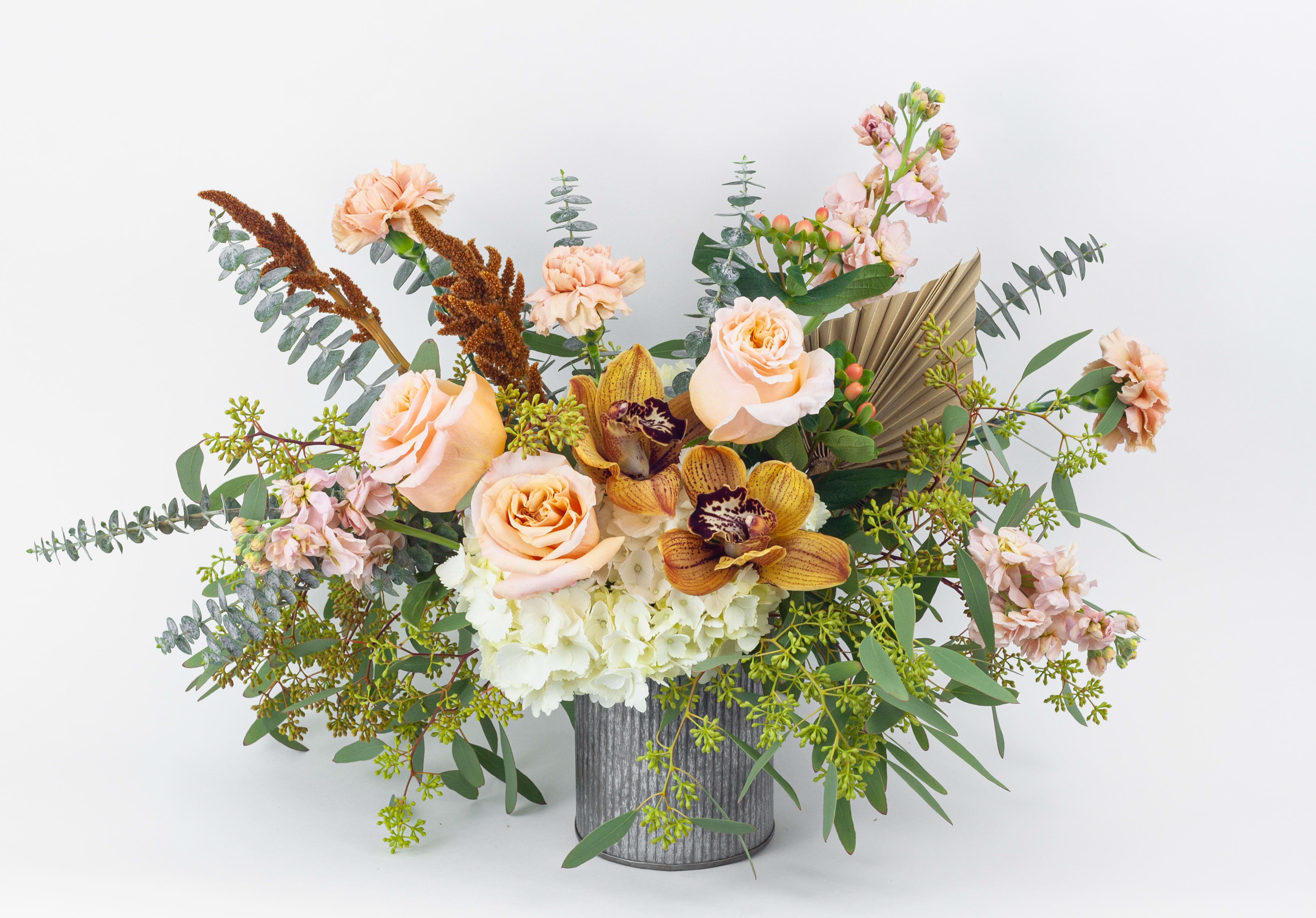 Peach roses and orchids in a ribbed metal vase