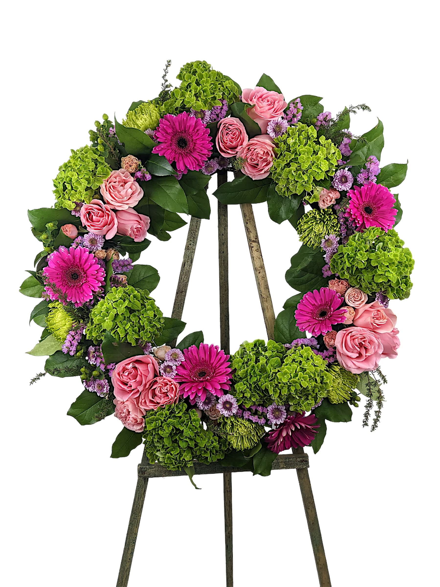 Floral wreath of pink roses, magenta daisies, and green hydrangeas on an easel