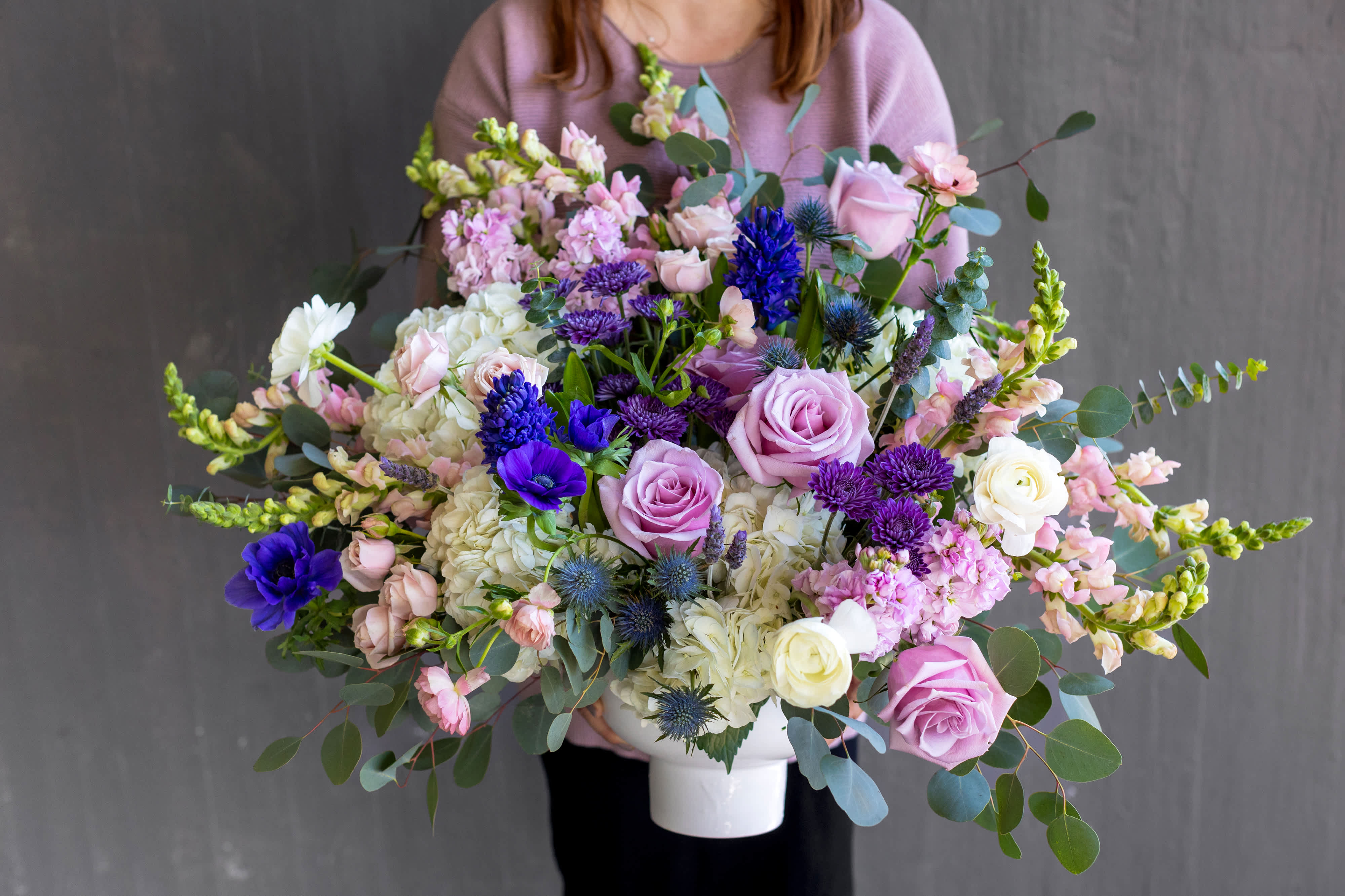 Large mixed bouquet in a white vase with pink, white, and purple flowers