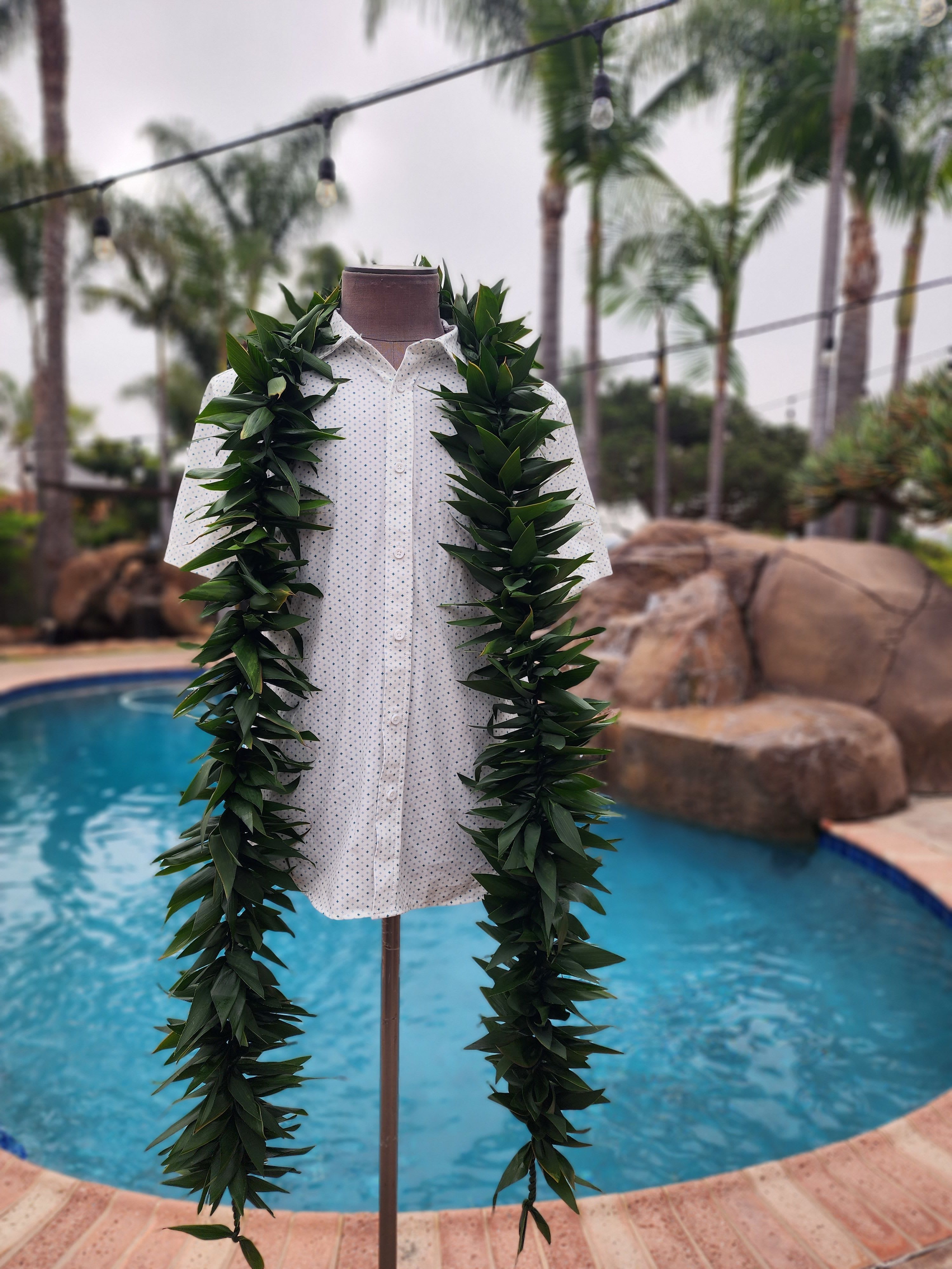 Leafy green lei draped over a white shirt on a mannequin