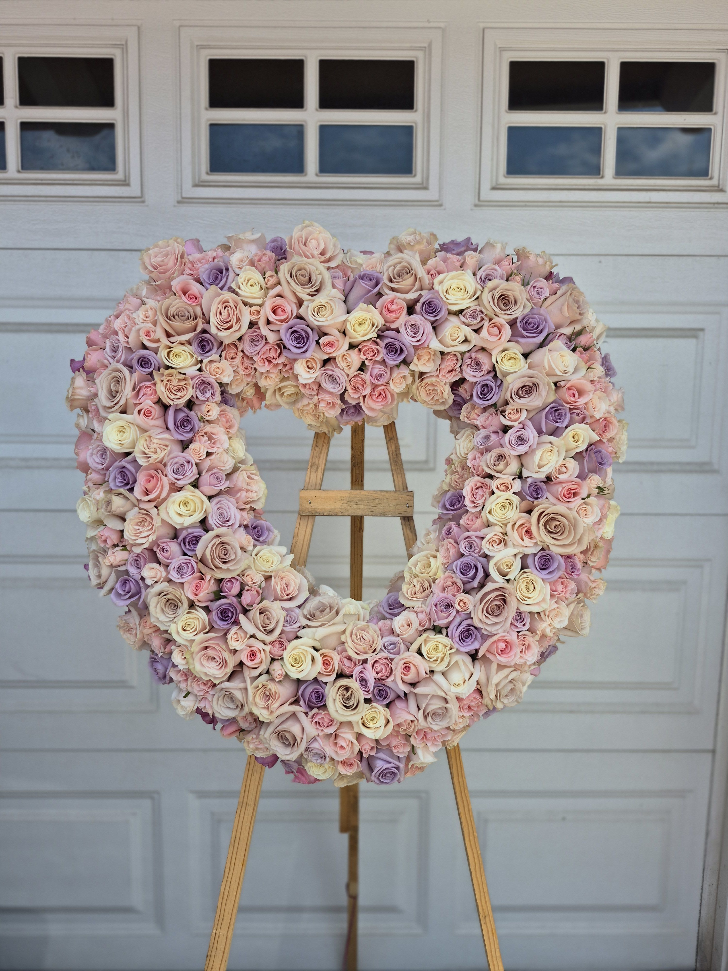 Heart-shaped rose arrangement on an easel in pastel pink, lavender, and cream