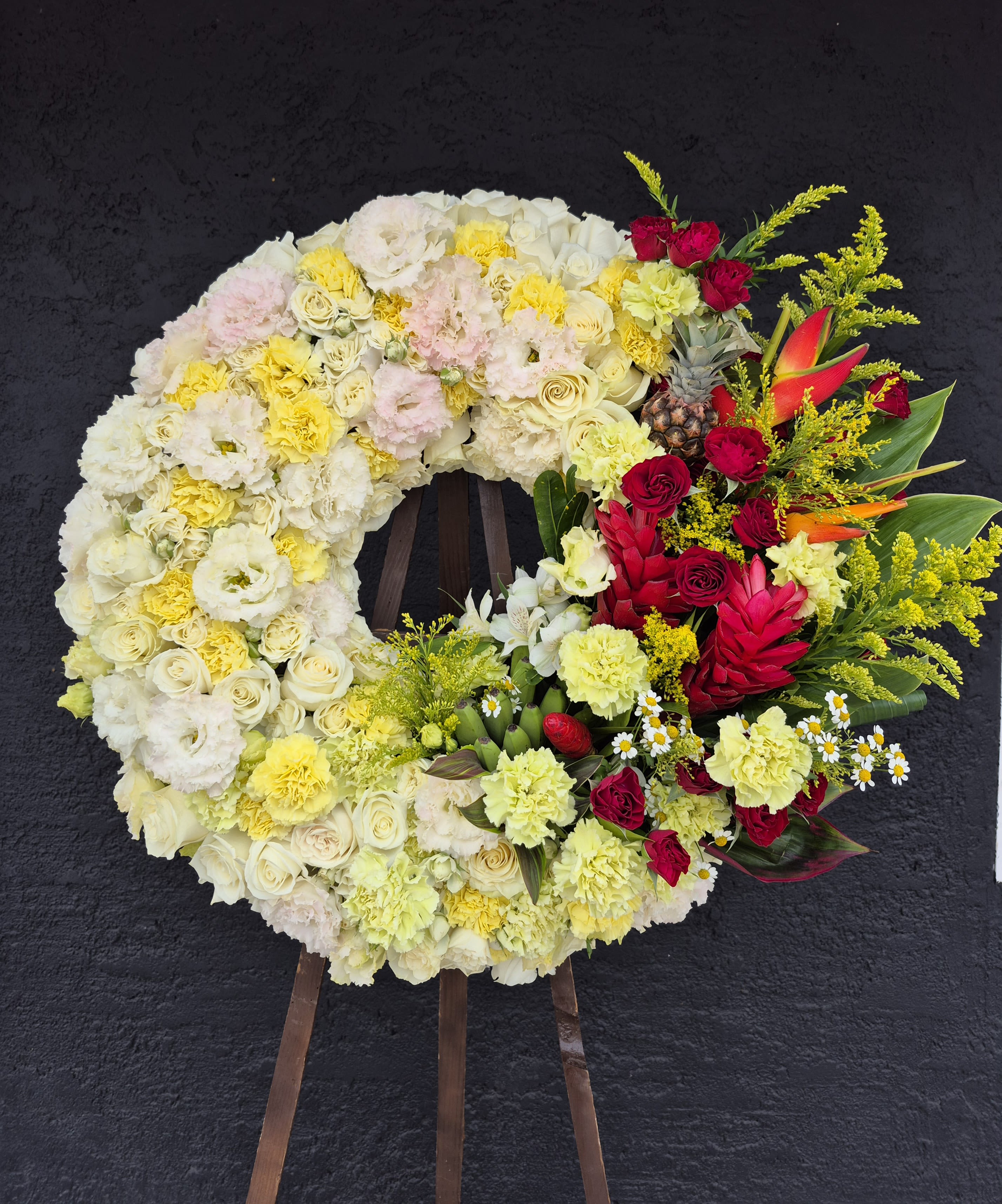 Large floral wreath with cream, yellow, pink, and red flowers on an easel