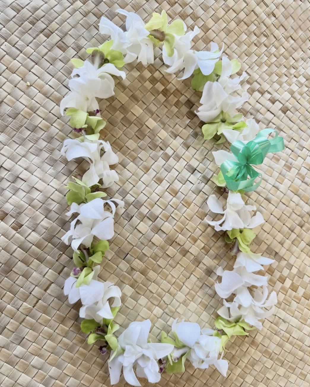 White and green flower lei on a woven mat