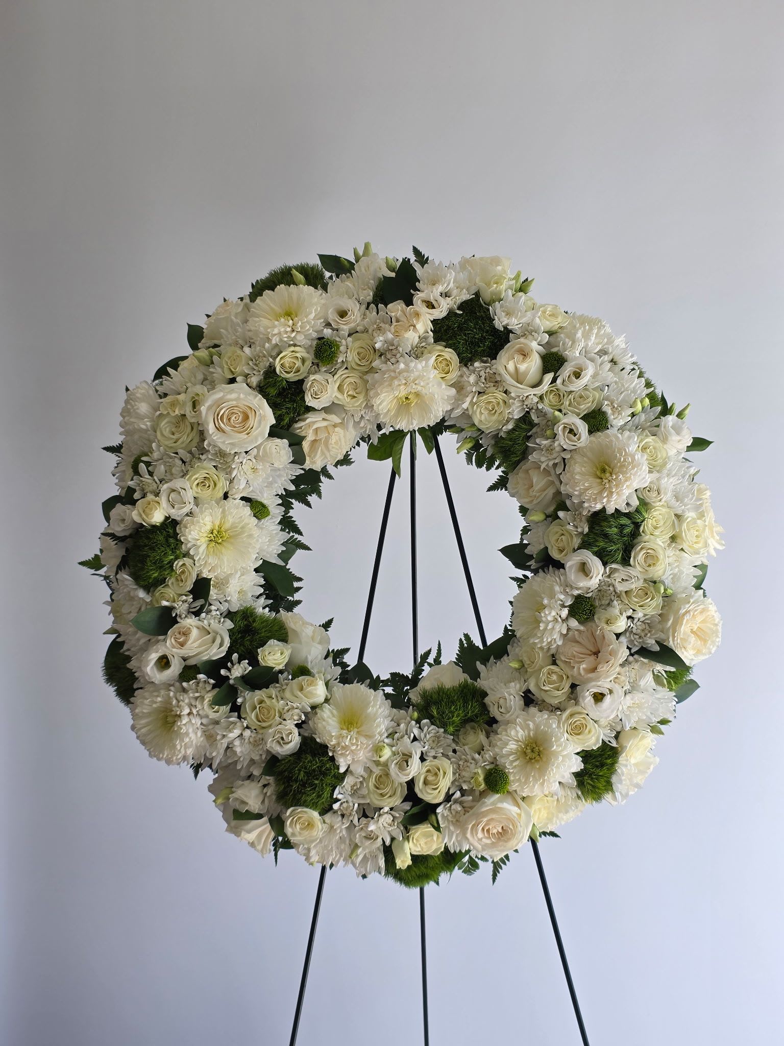 White floral wreath on a black stand