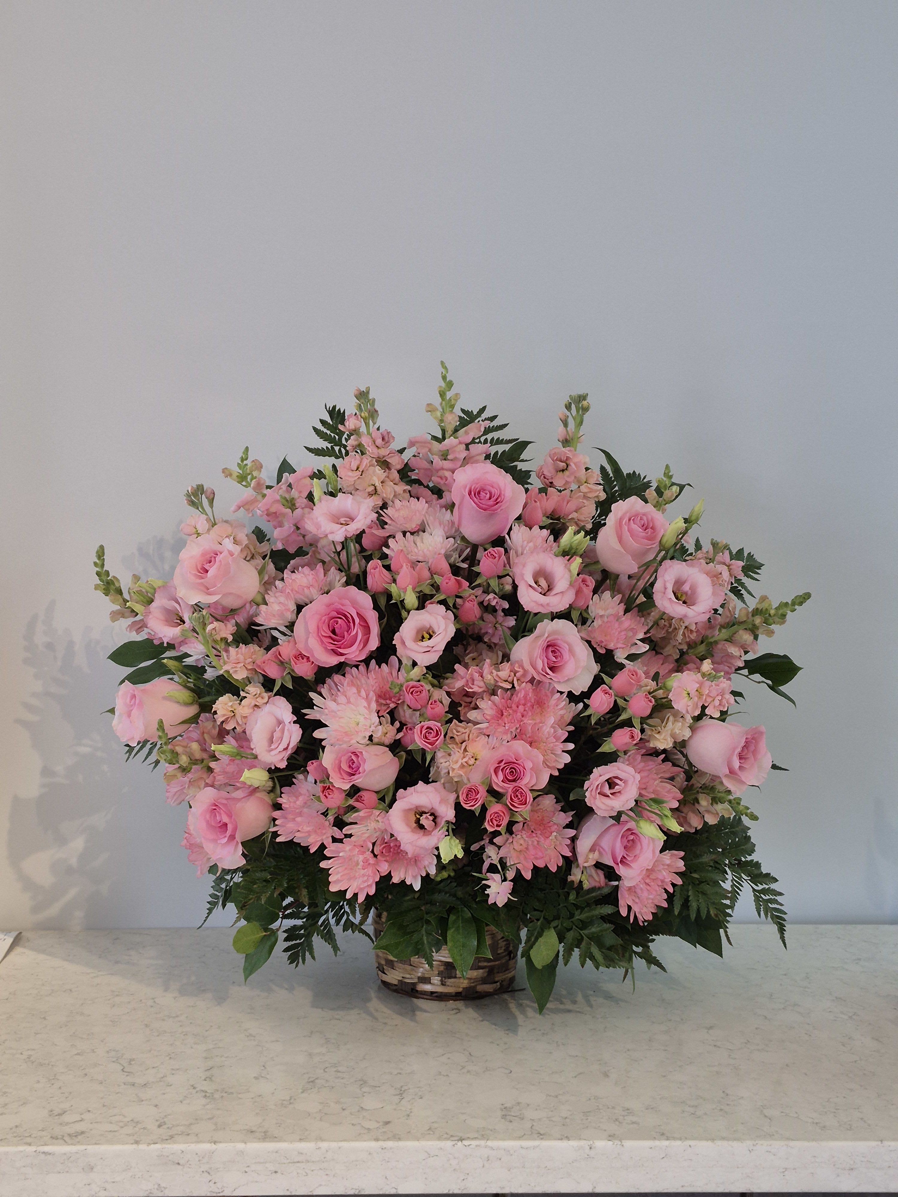 Large pink flower arrangement in a woven basket