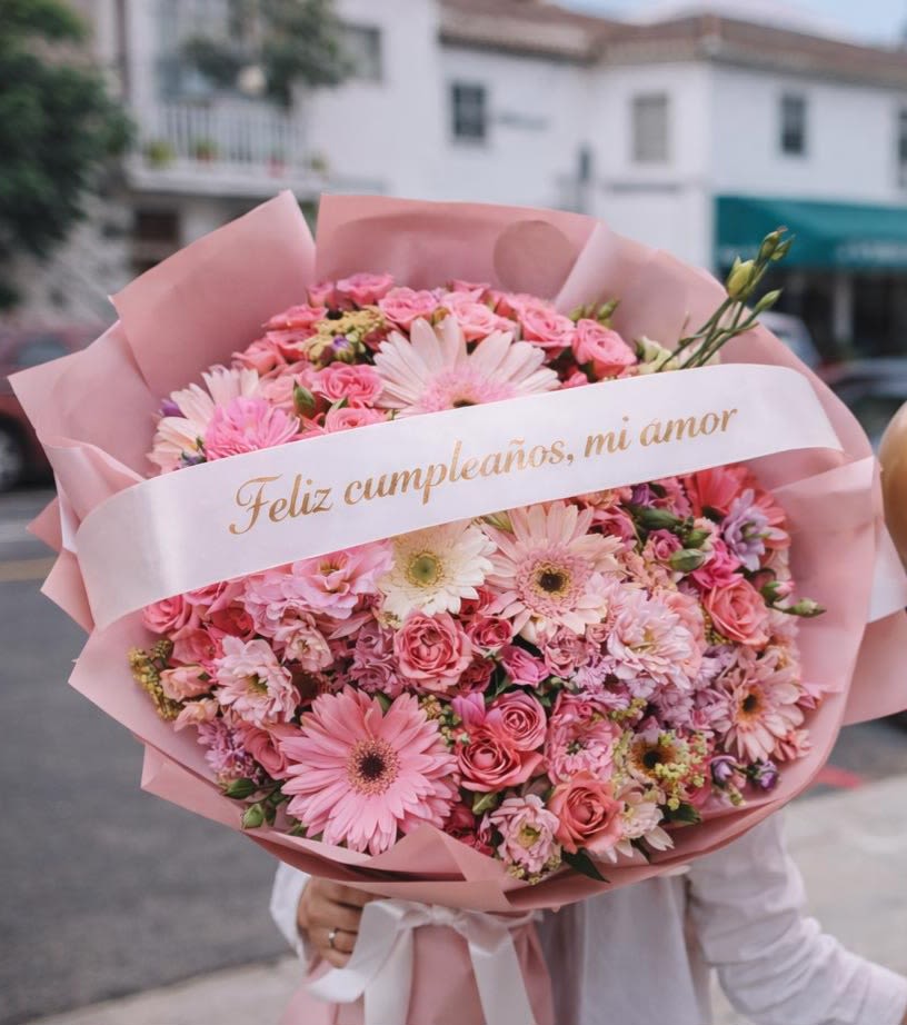 Pink mixed flower bouquet wrapped in pink paper with a birthday ribbon