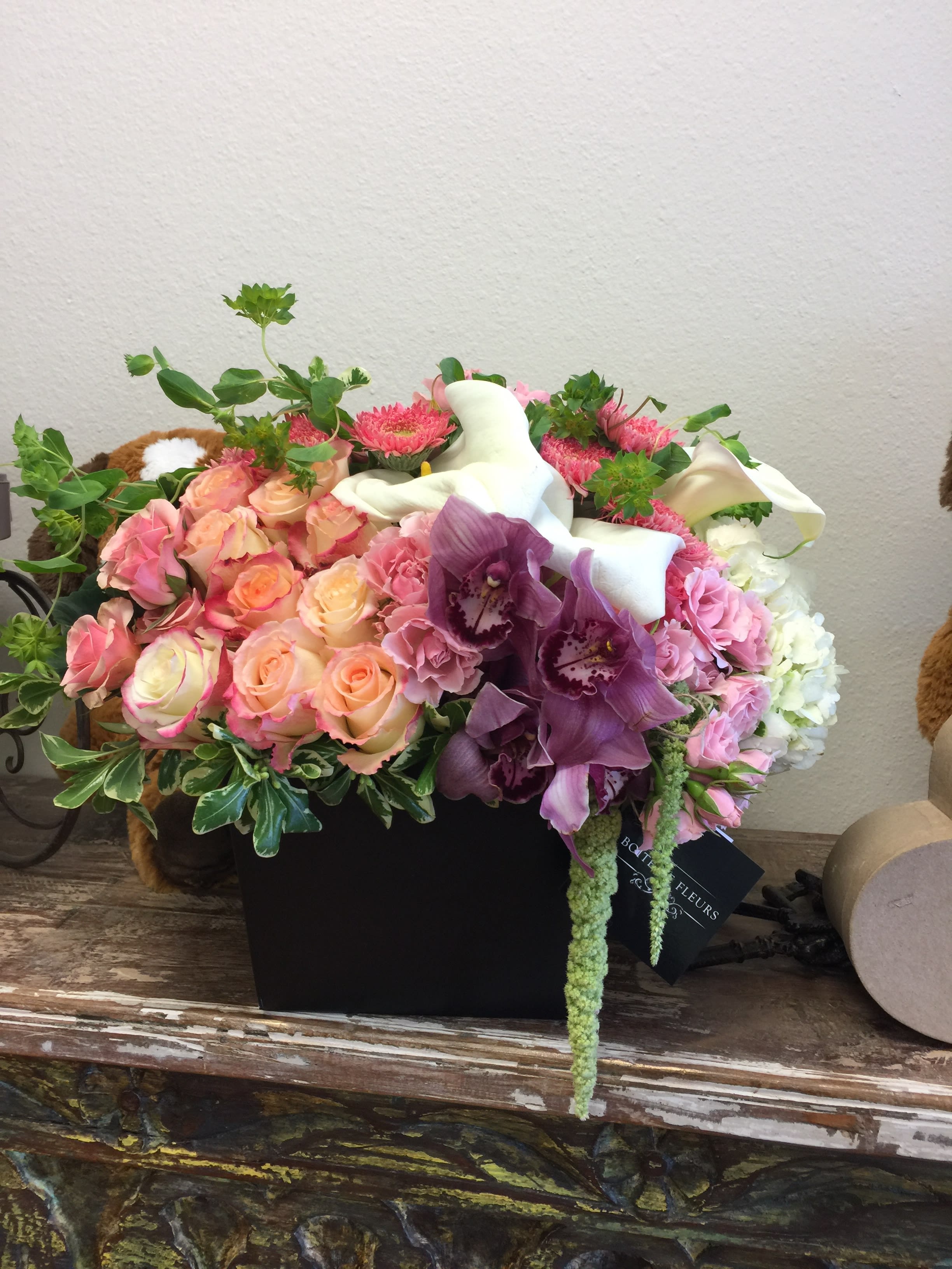 Mixed bouquet of pink roses, purple orchids, and white calla lilies in a black box