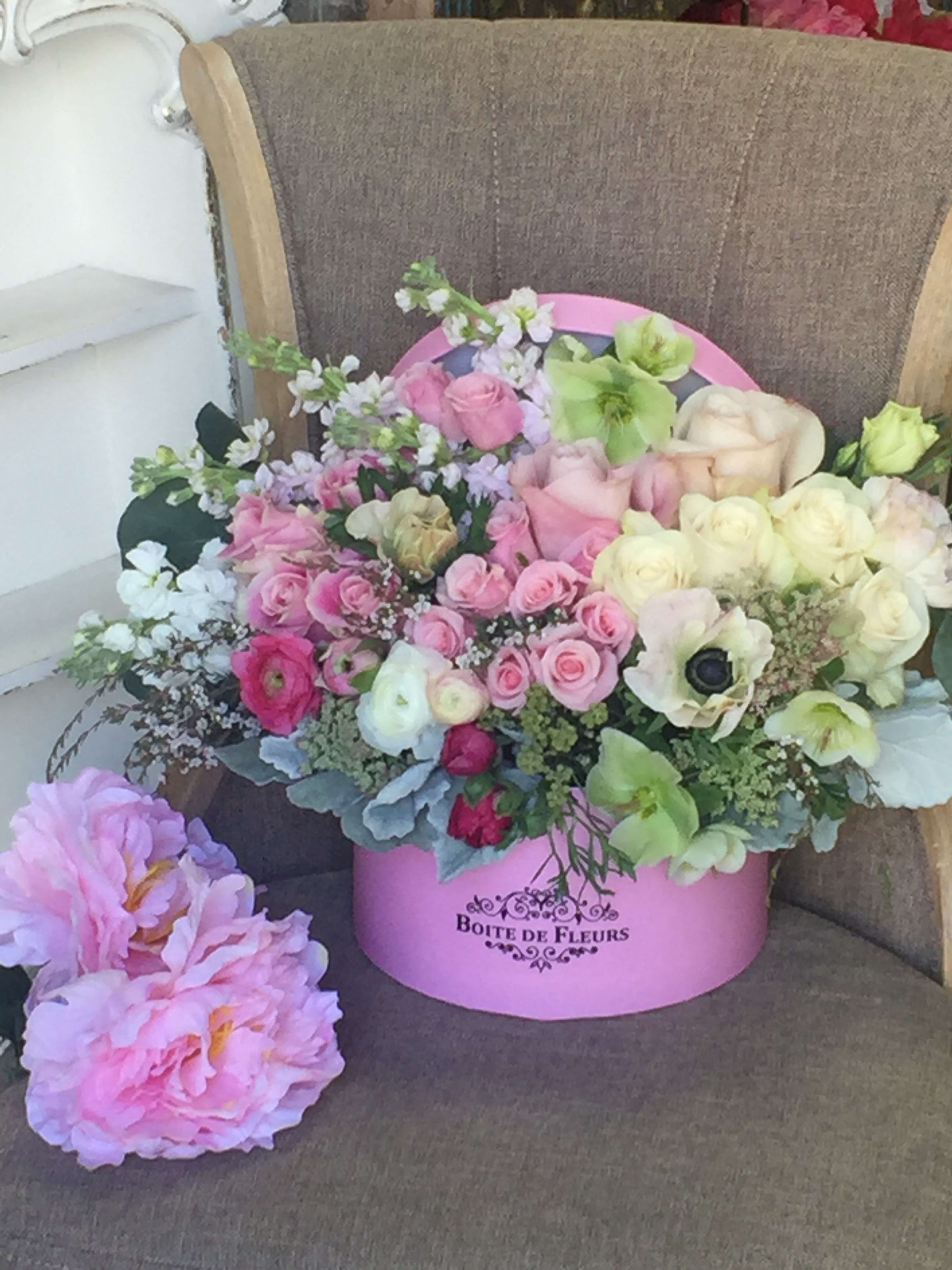 Pink and cream roses arranged in a pink hat box with pastel blooms