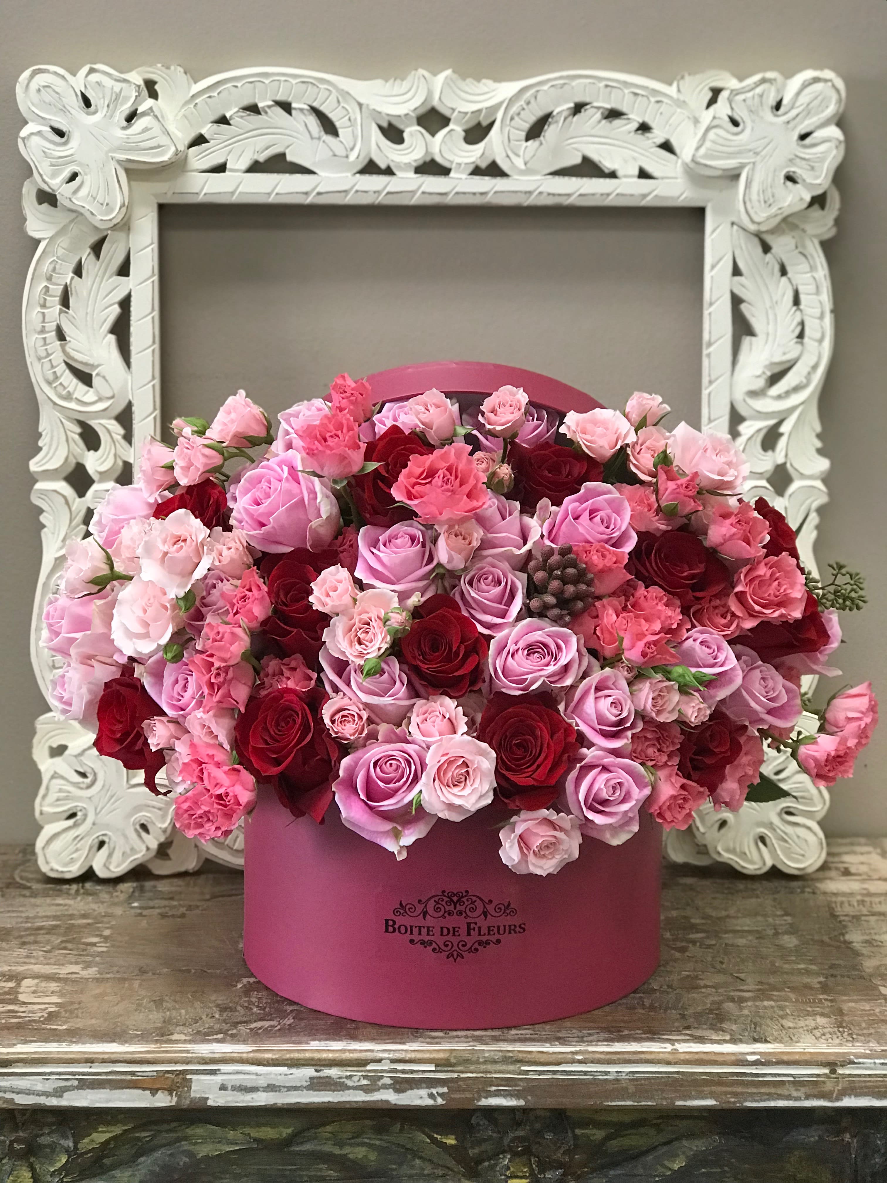Pink and red roses arranged in a round pink box