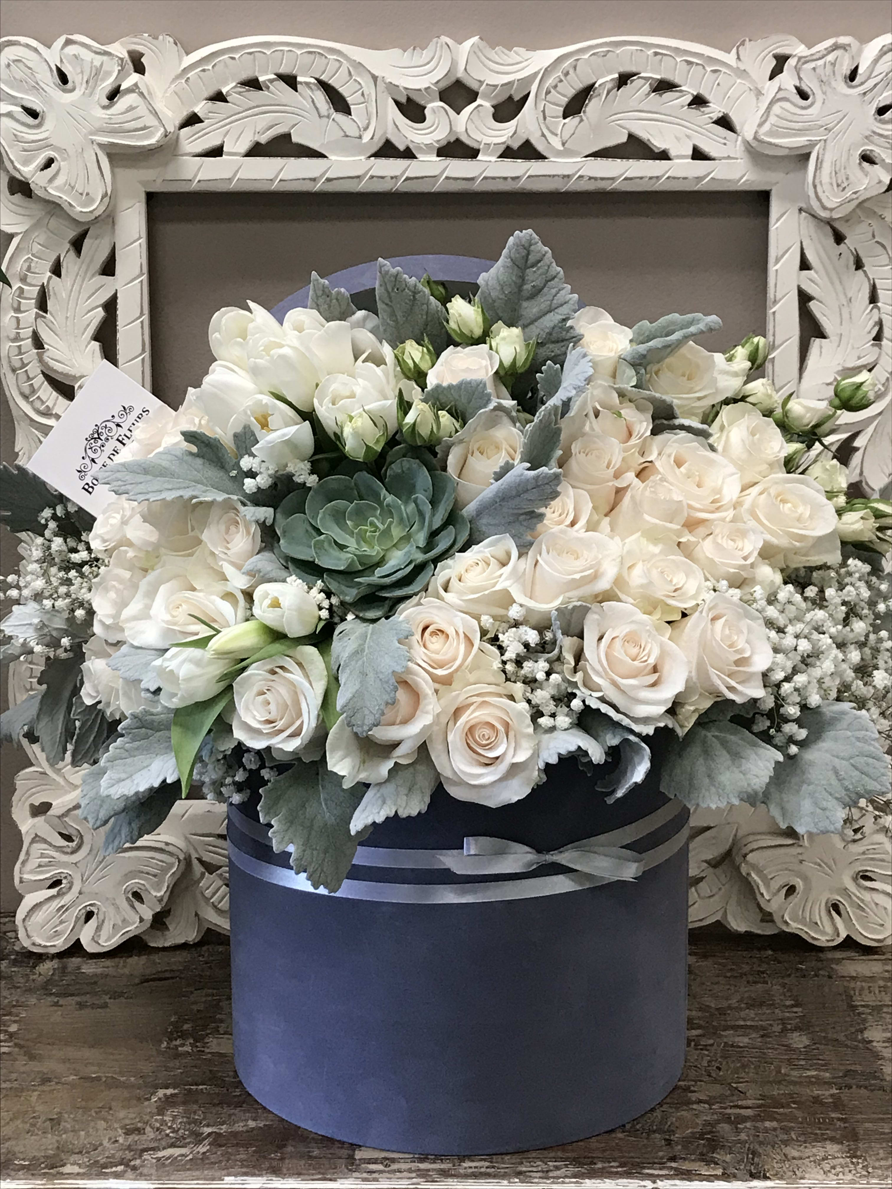 Cream roses and white blooms in a navy hatbox with silver ribbon