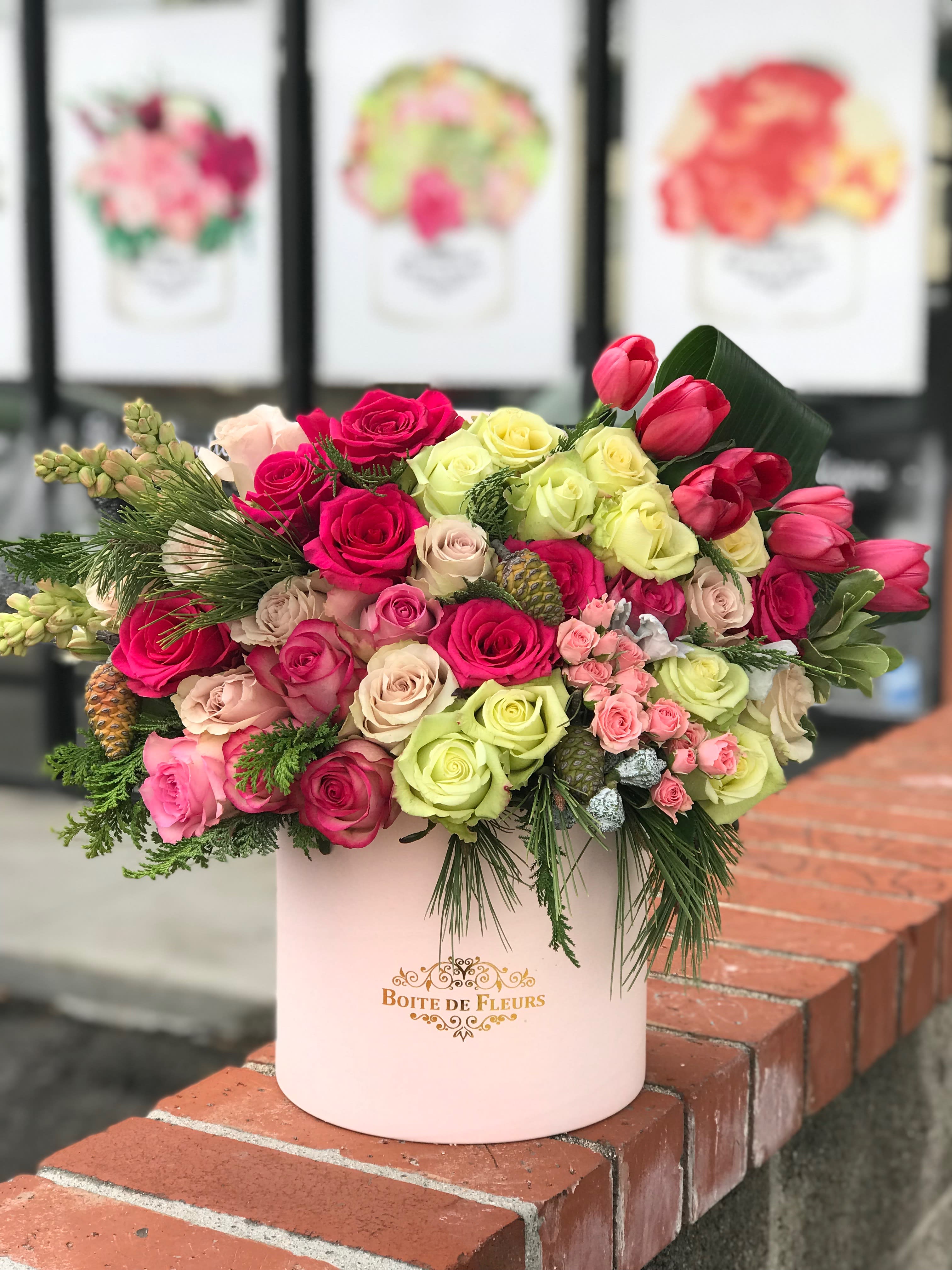 Mixed roses and tulips arranged in a pink hatbox