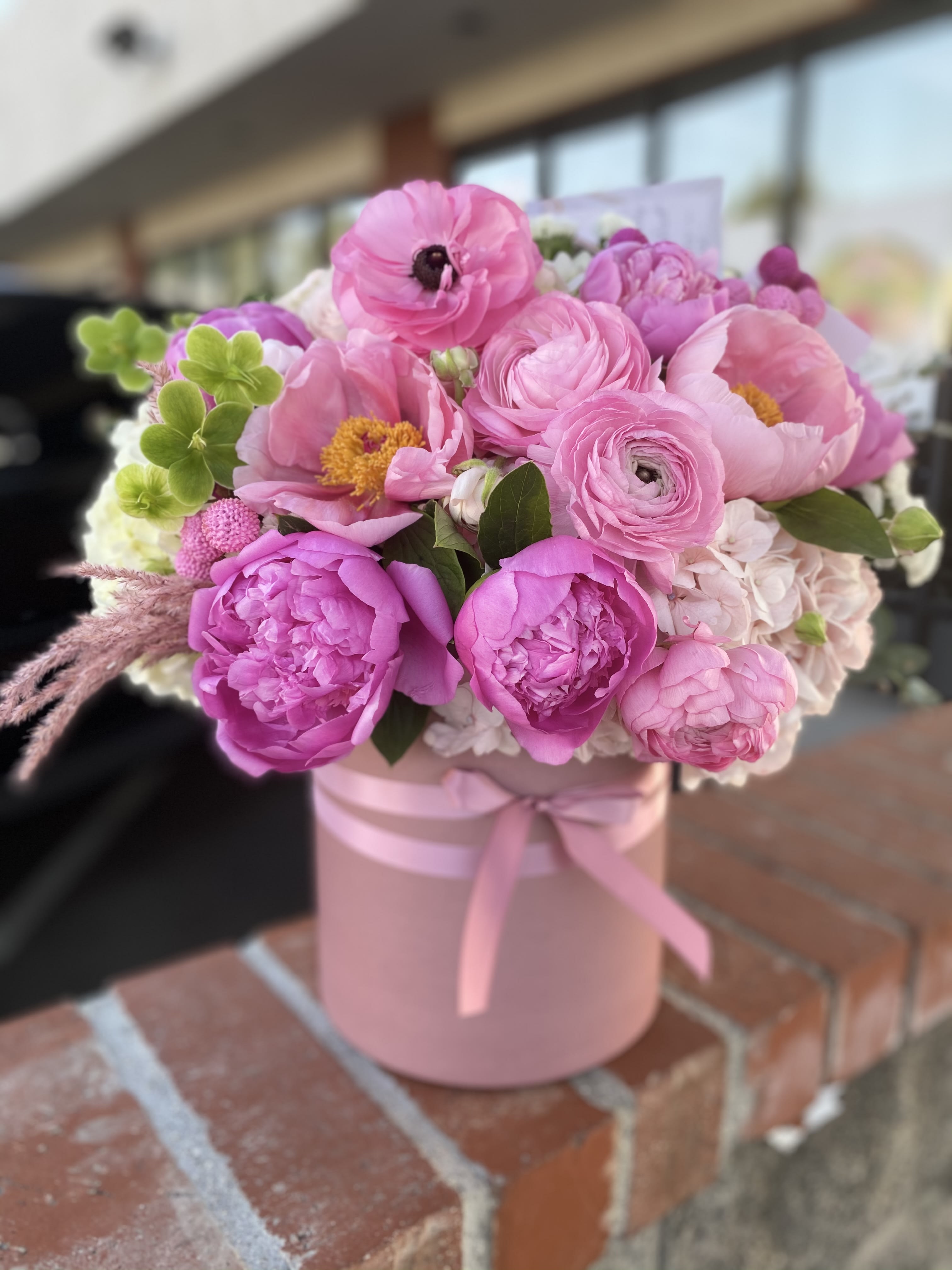 Pink bouquet in a round pink box tied with ribbon