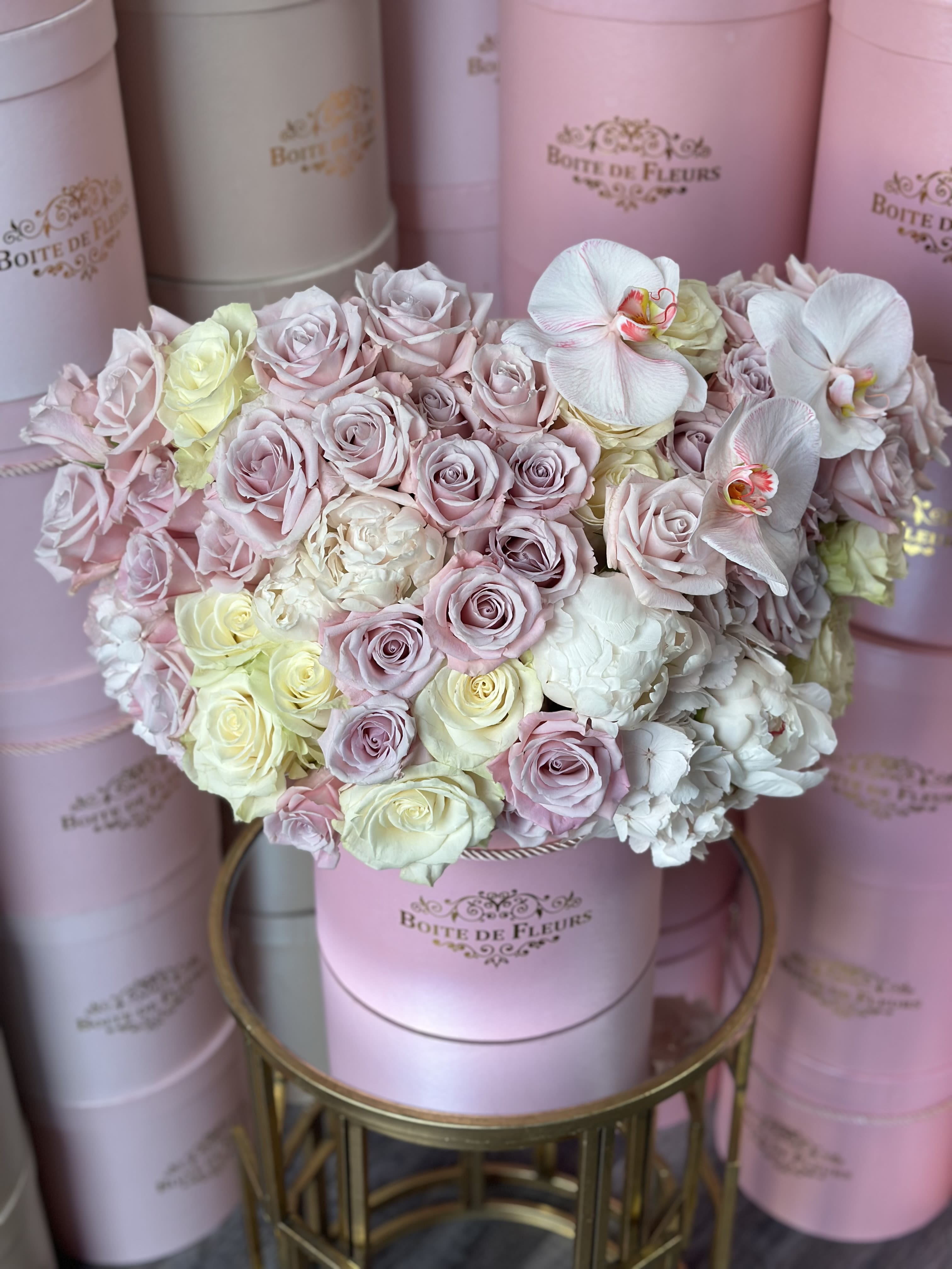 Pastel rose bouquet in a pink hat box with white orchids