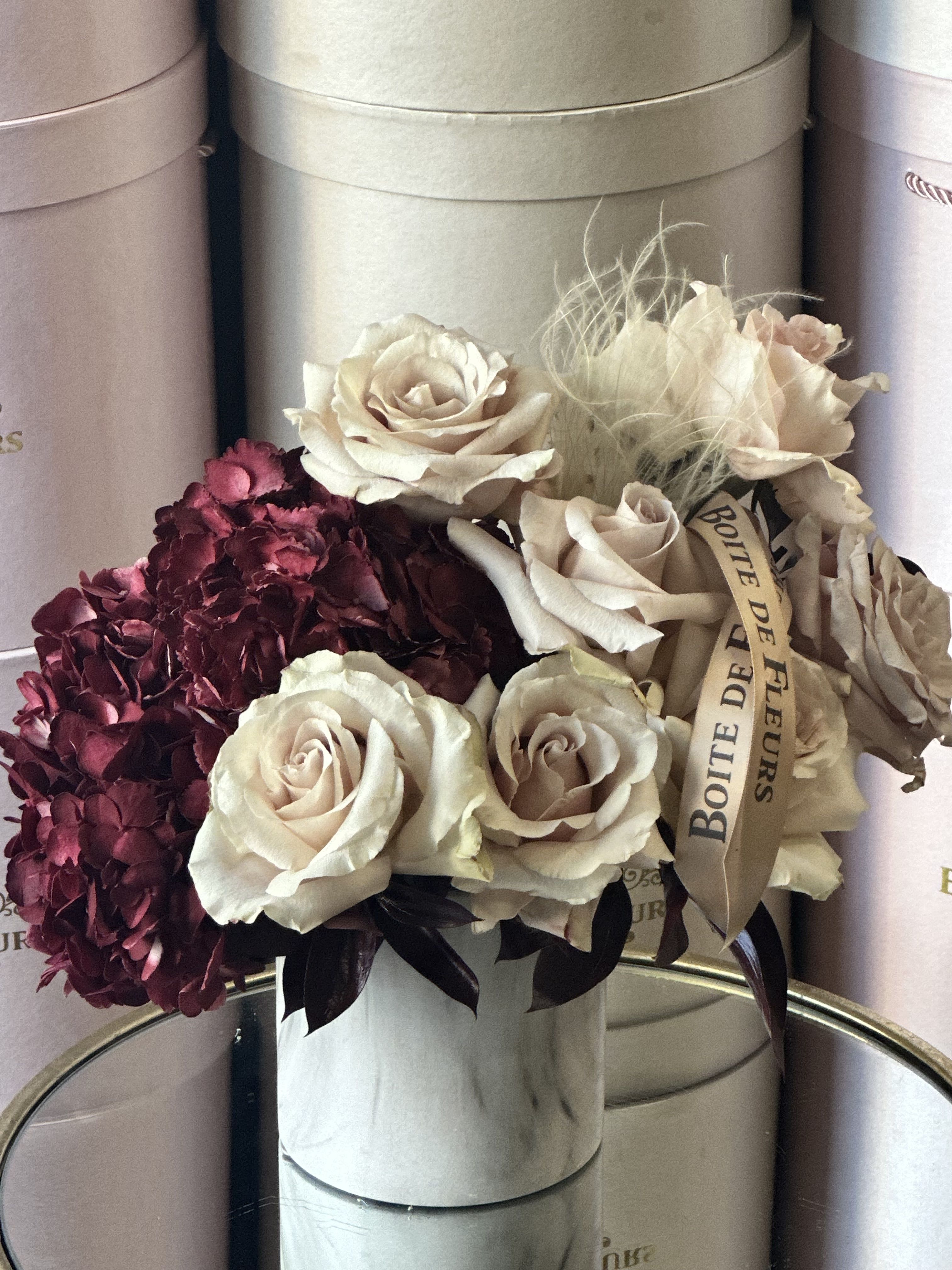 Bouquet of cream roses and burgundy hydrangeas in a round box