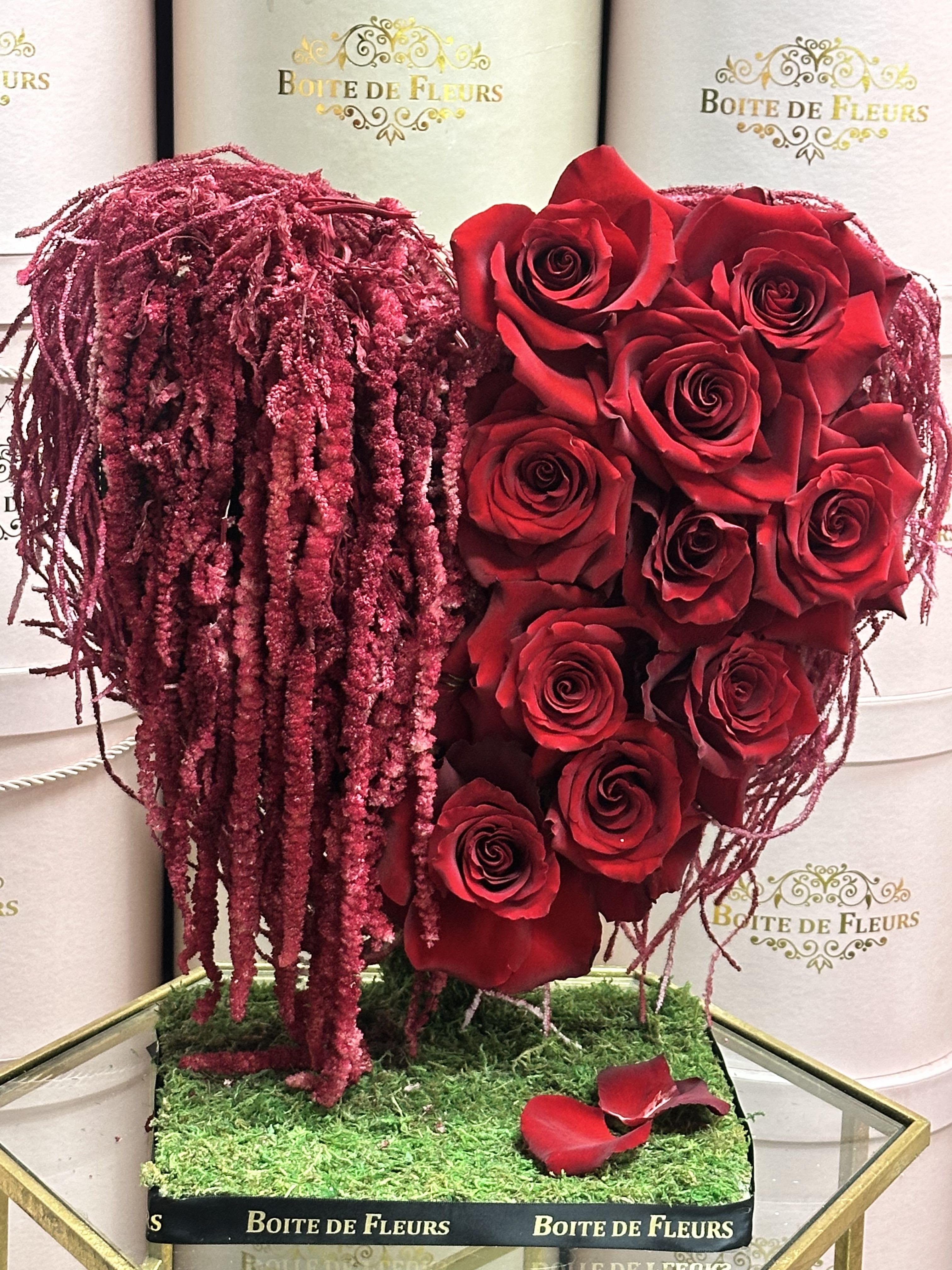Red roses arranged in a heart shape with burgundy hanging accents