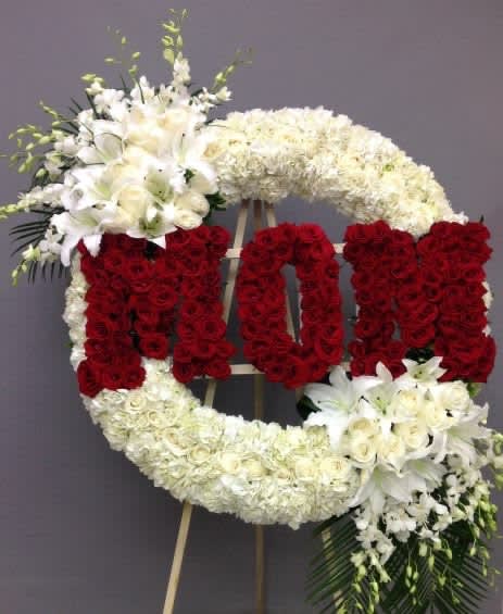 Large floral standing wreath with red and white flowers on an easel