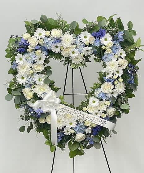 Heart-shaped floral wreath on a stand with a white ribbon