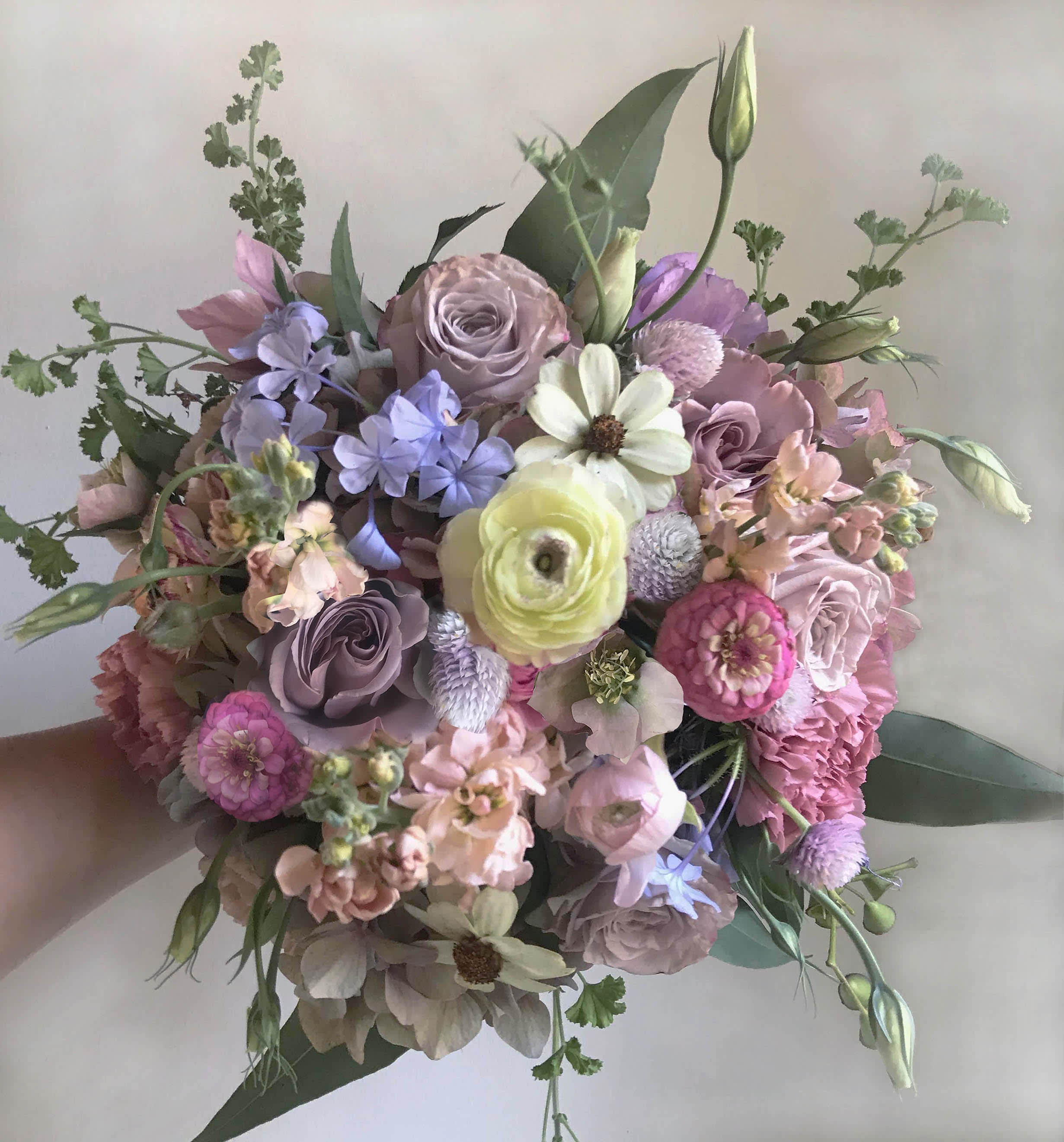 Handheld bouquet of pastel flowers in pink, lavender, and cream