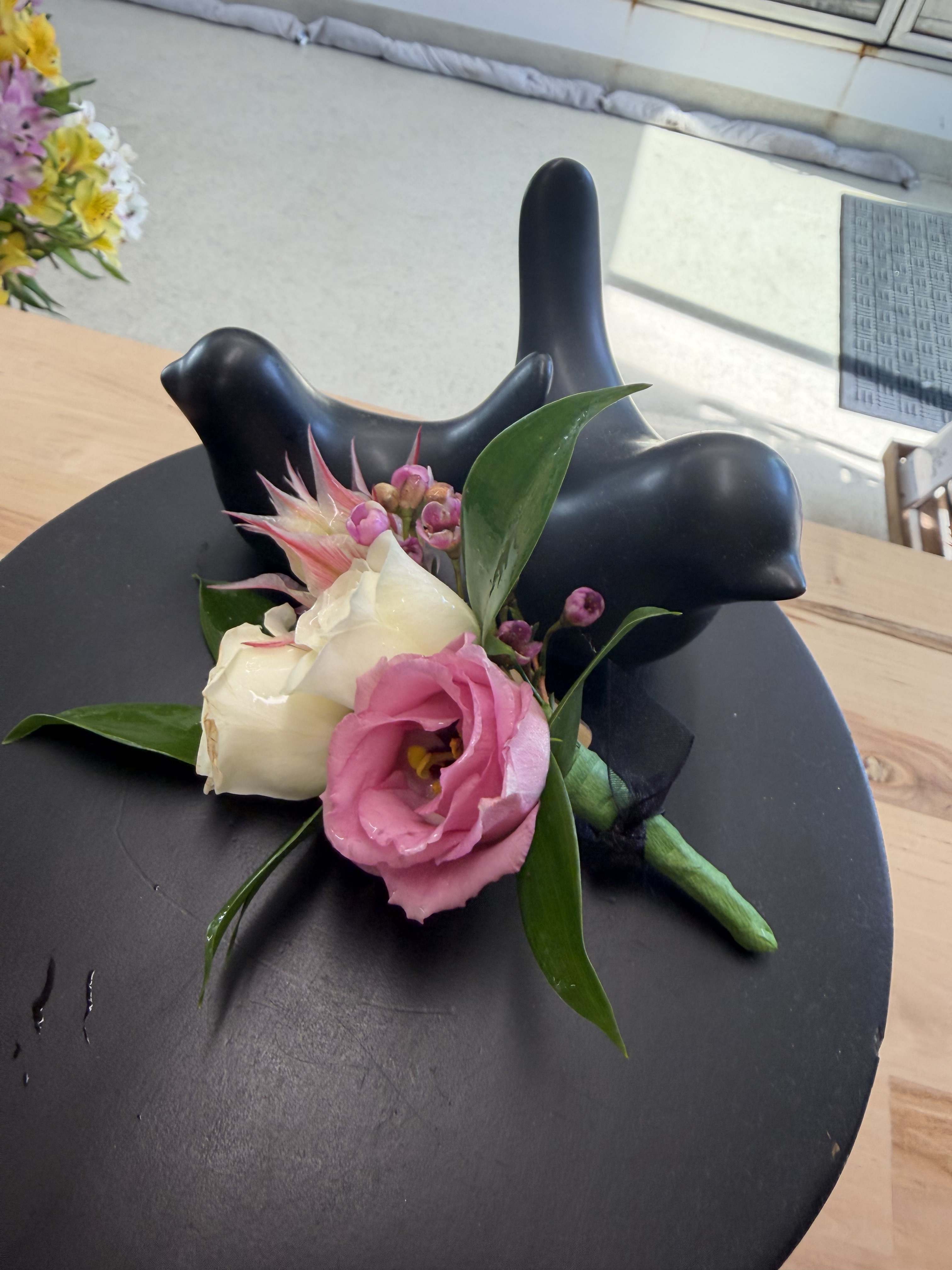 Small boutonniere with pink and white flowers on a black display stand