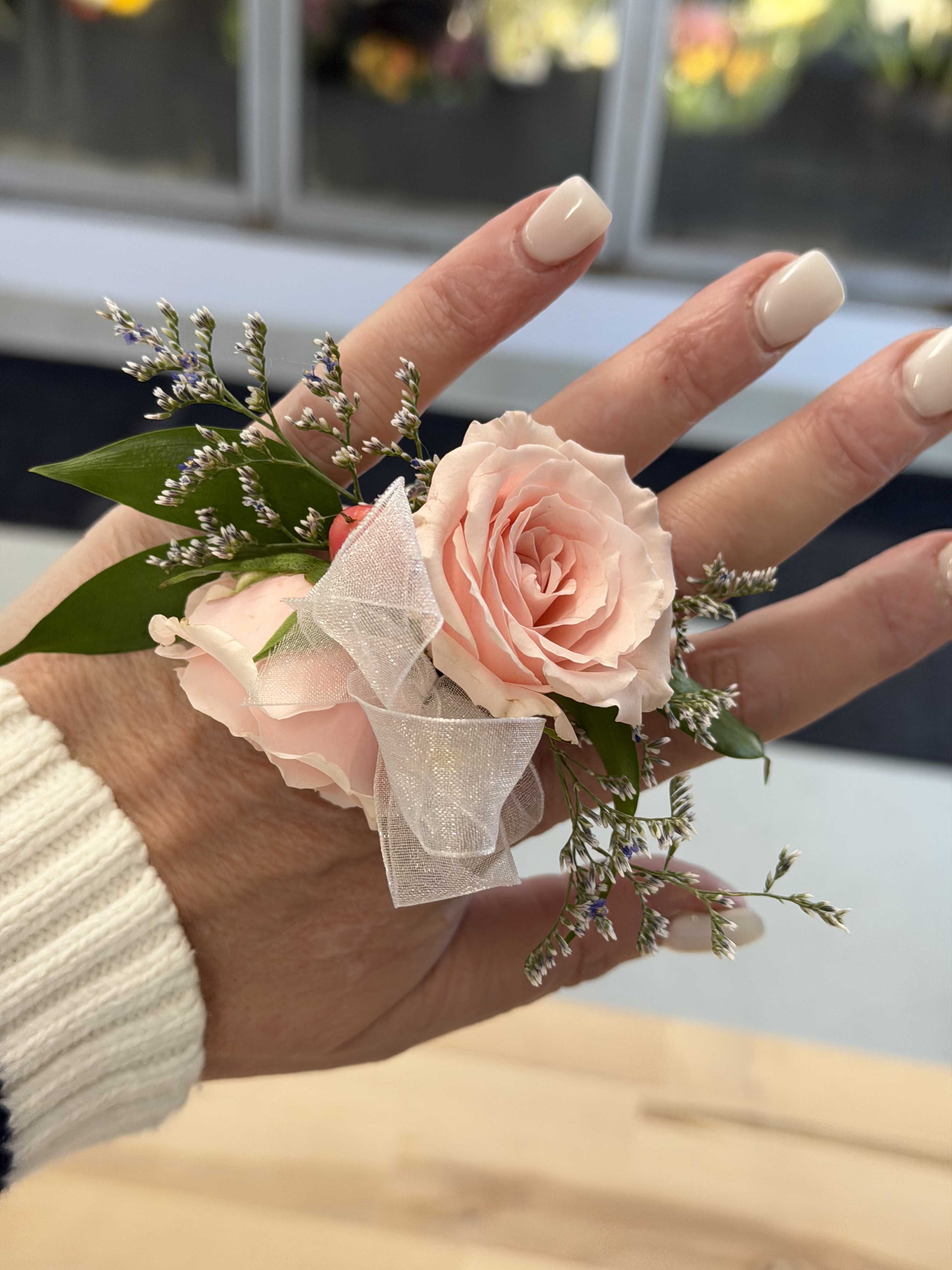 Small blush rose corsage with ribbon on a hand