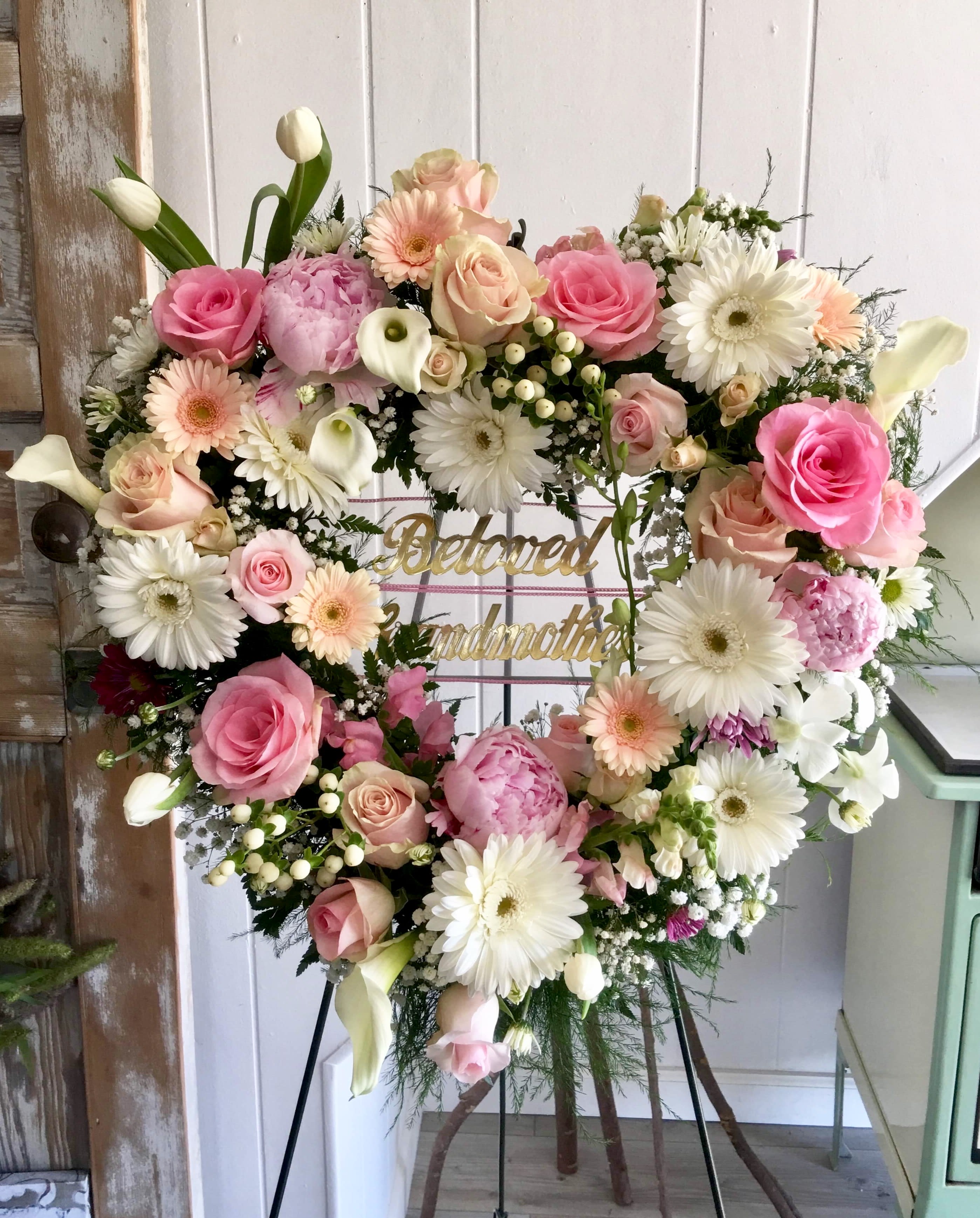 Heart-shaped floral wreath with pink and white flowers on an easel