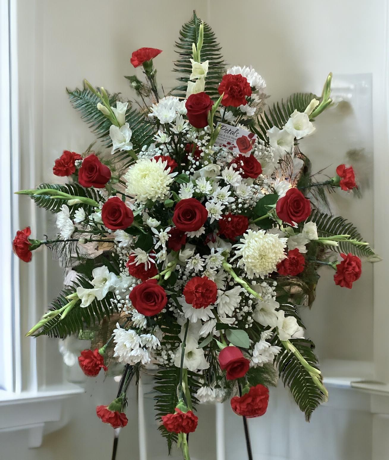 Standing floral spray with red roses, white flowers, and carnations