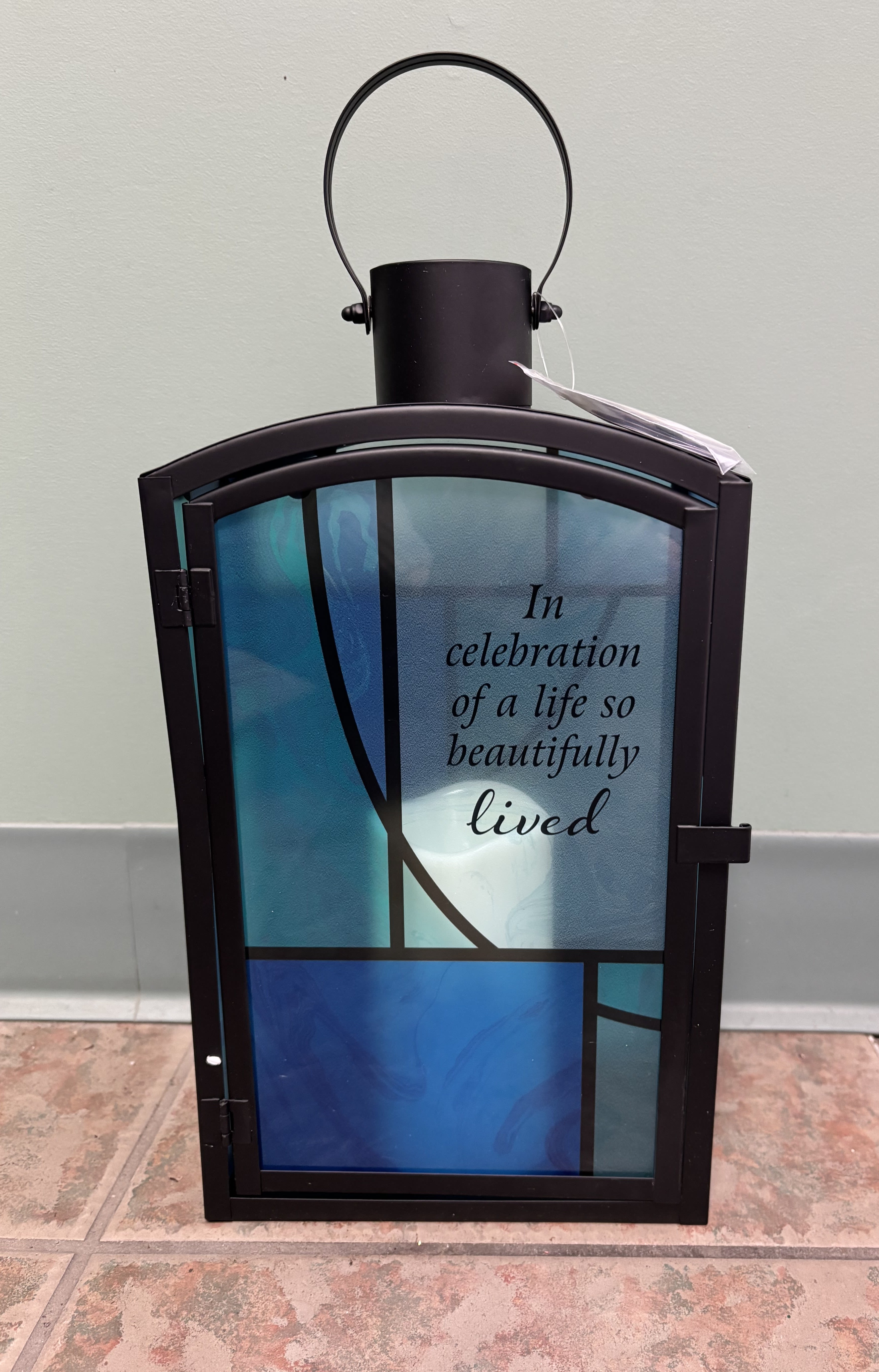 Decorative memorial lantern with blue glass panels and a sympathy message