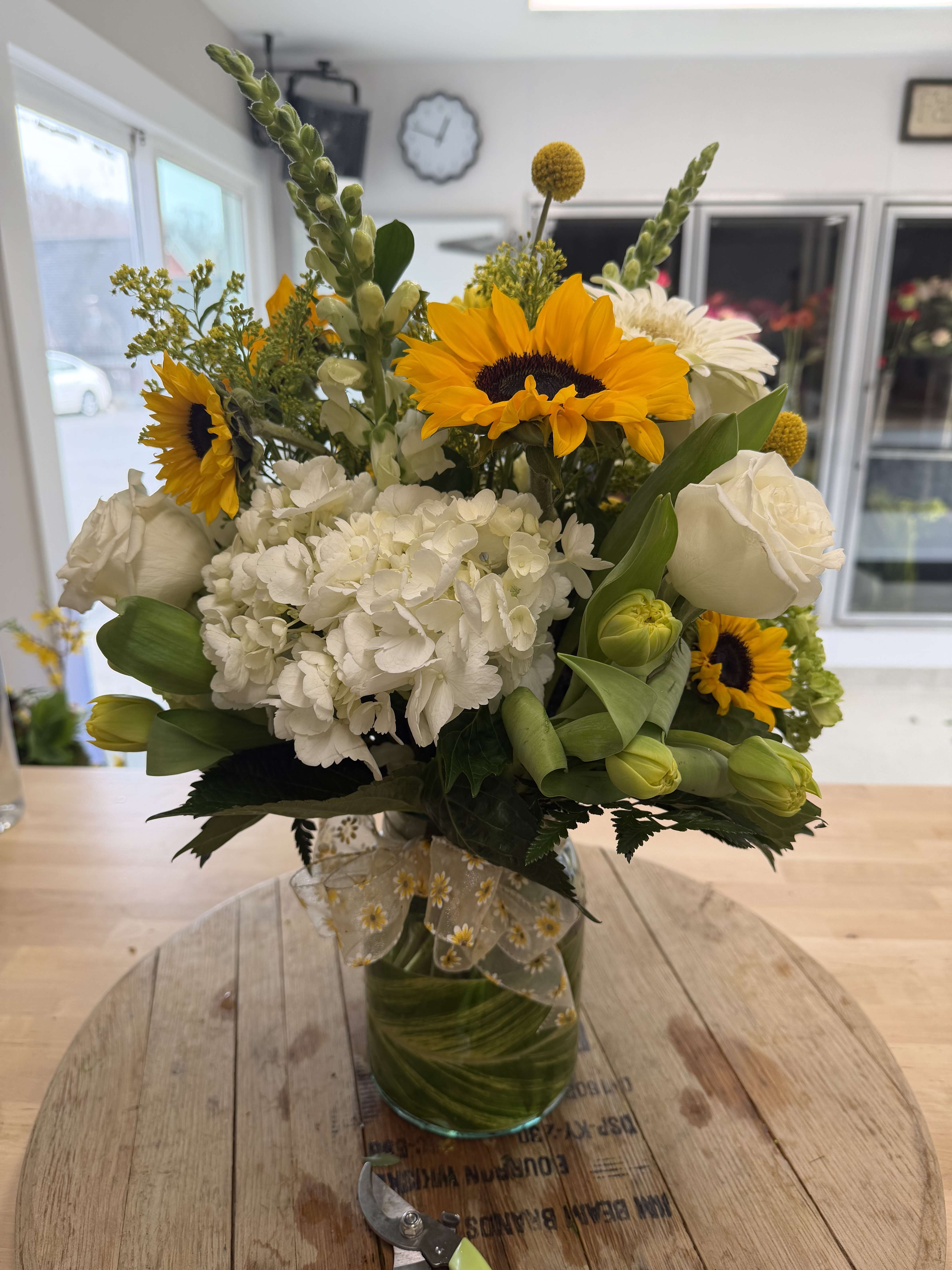 Bouquet of sunflowers, white hydrangea, and white roses in a glass vase