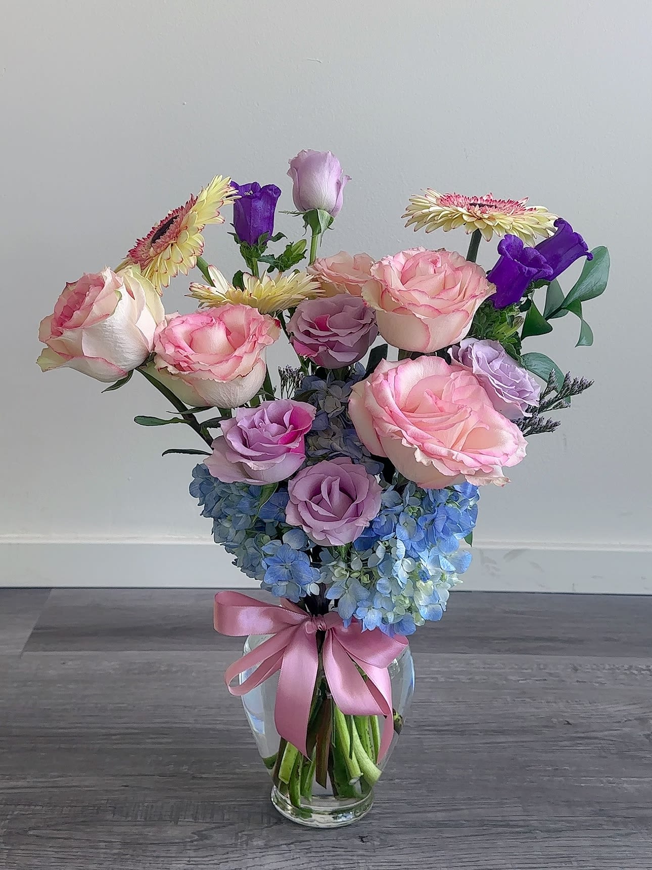 Pink and lavender roses with blue hydrangeas in a glass vase