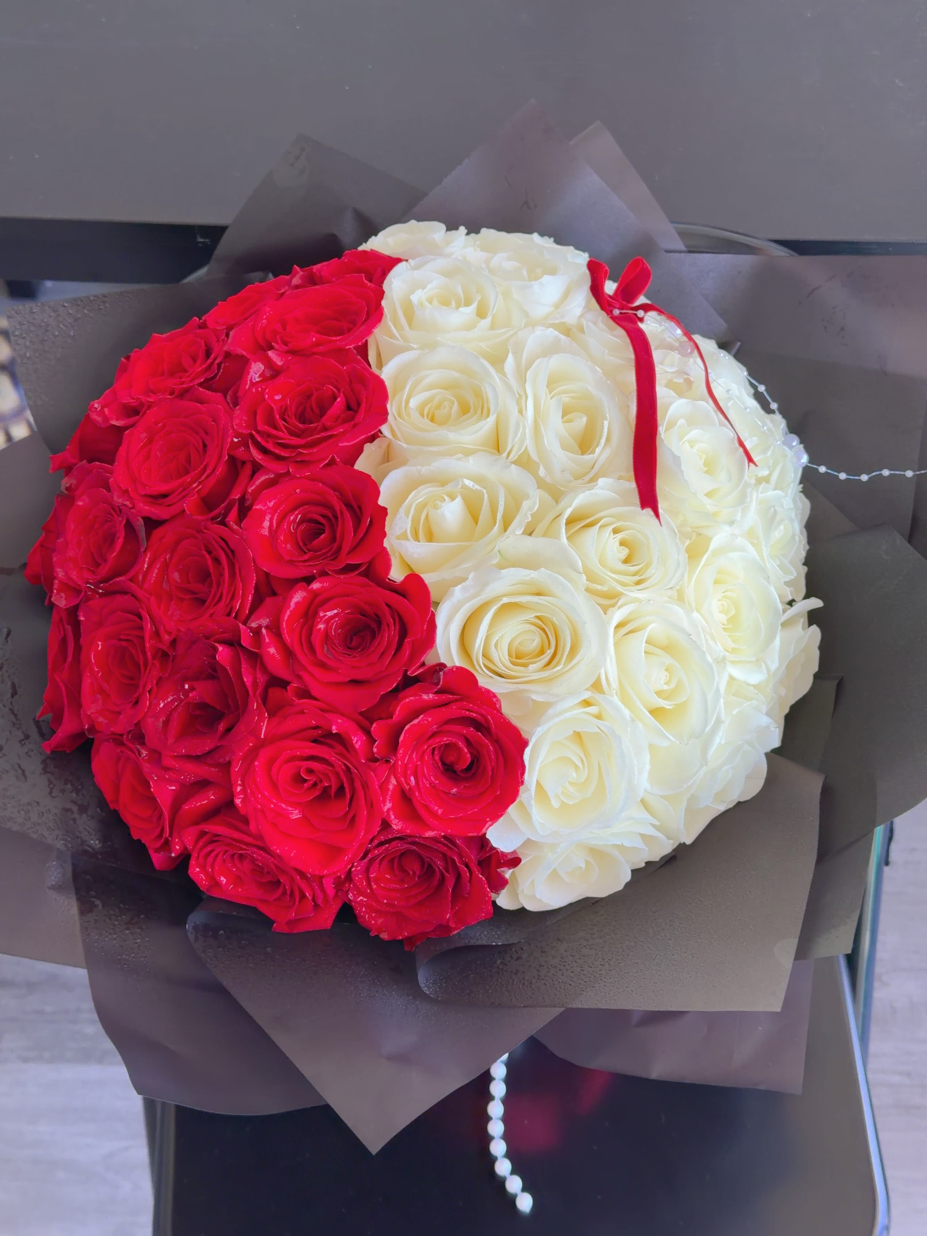 Red and white rose bouquet wrapped in dark paper