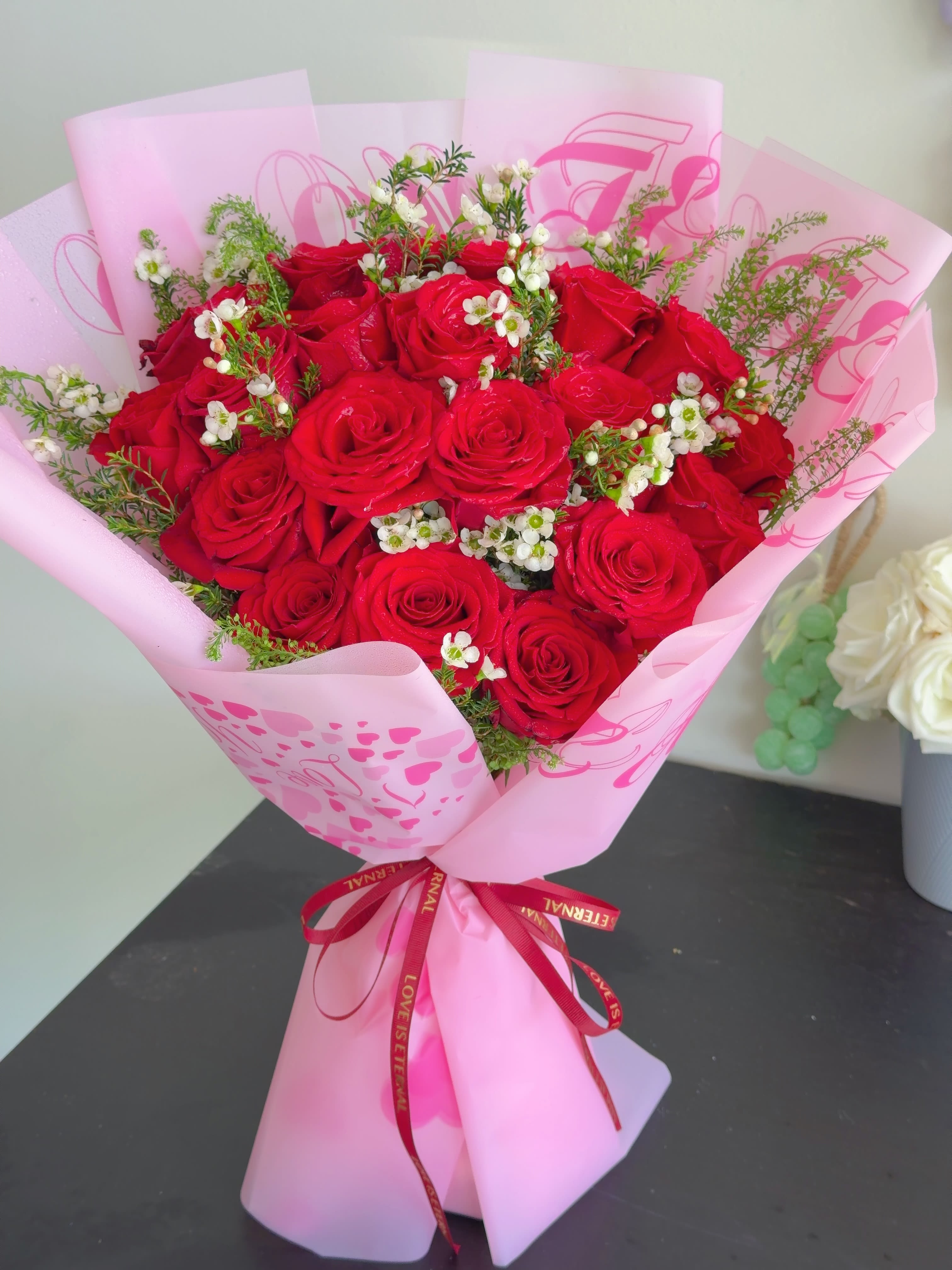 Bouquet of red roses wrapped in pink paper with a ribbon