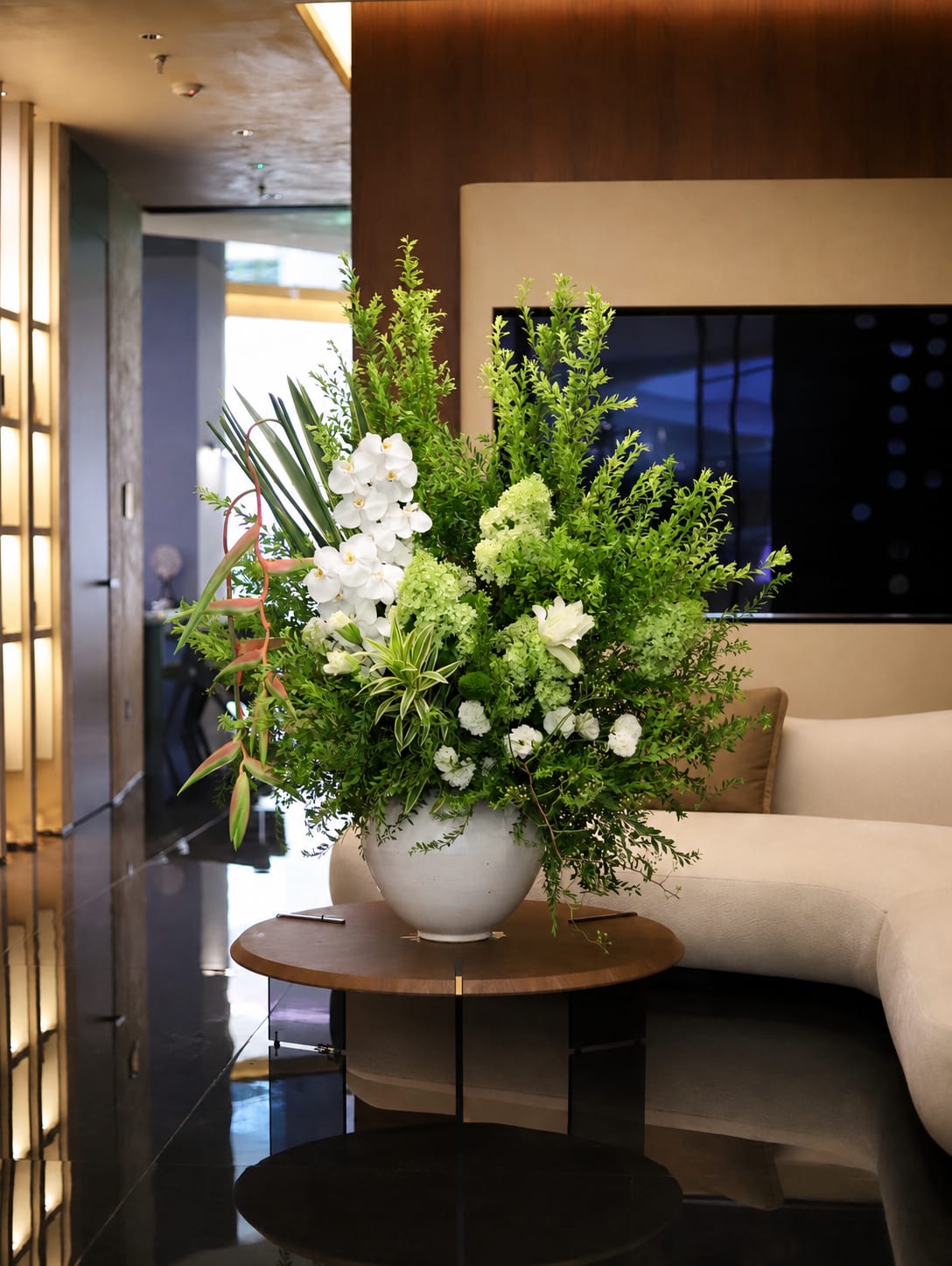 Large white and green floral arrangement in a round white vase