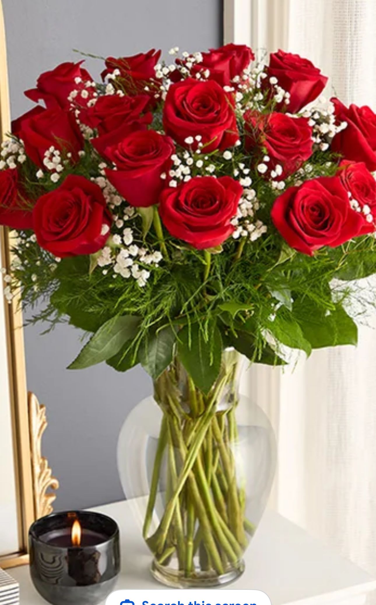 Red roses arranged in a clear glass vase with baby's breath