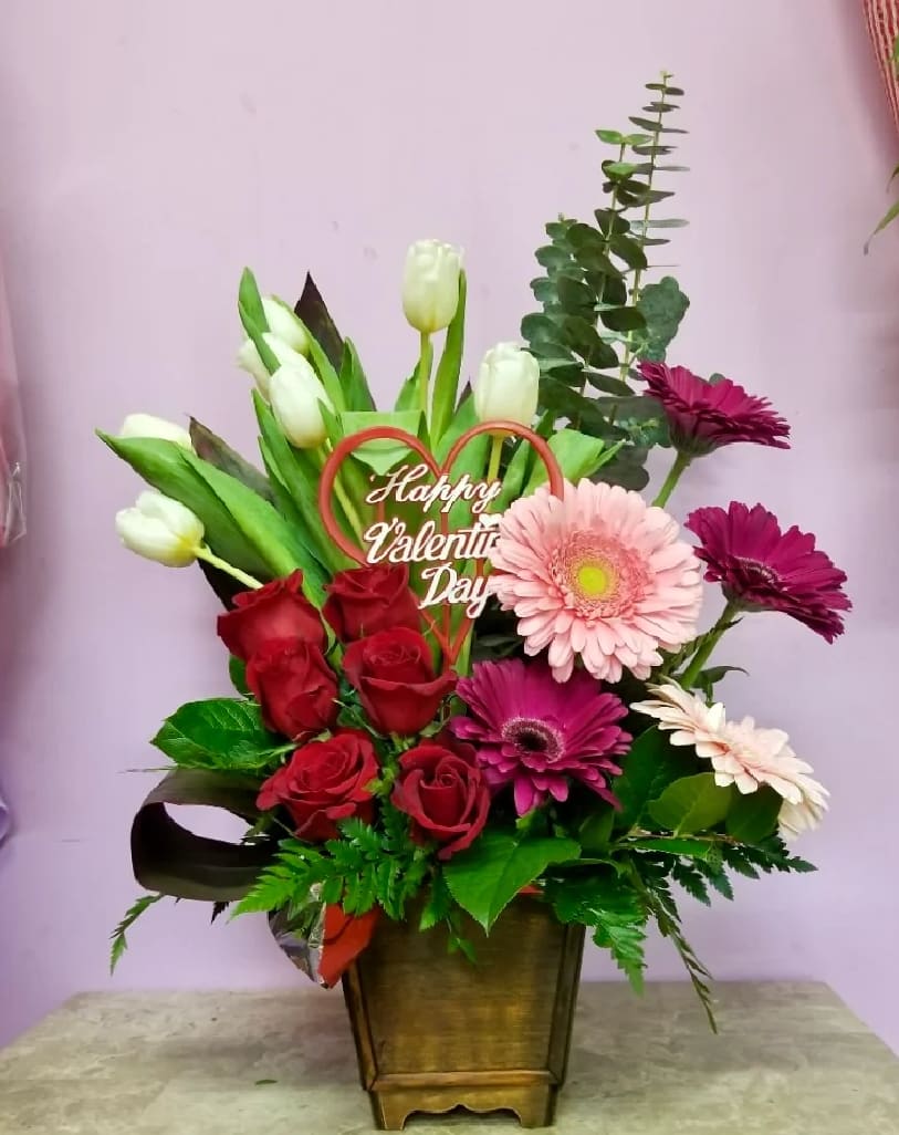 Mixed bouquet with roses, tulips, and gerbera daisies in a wooden container