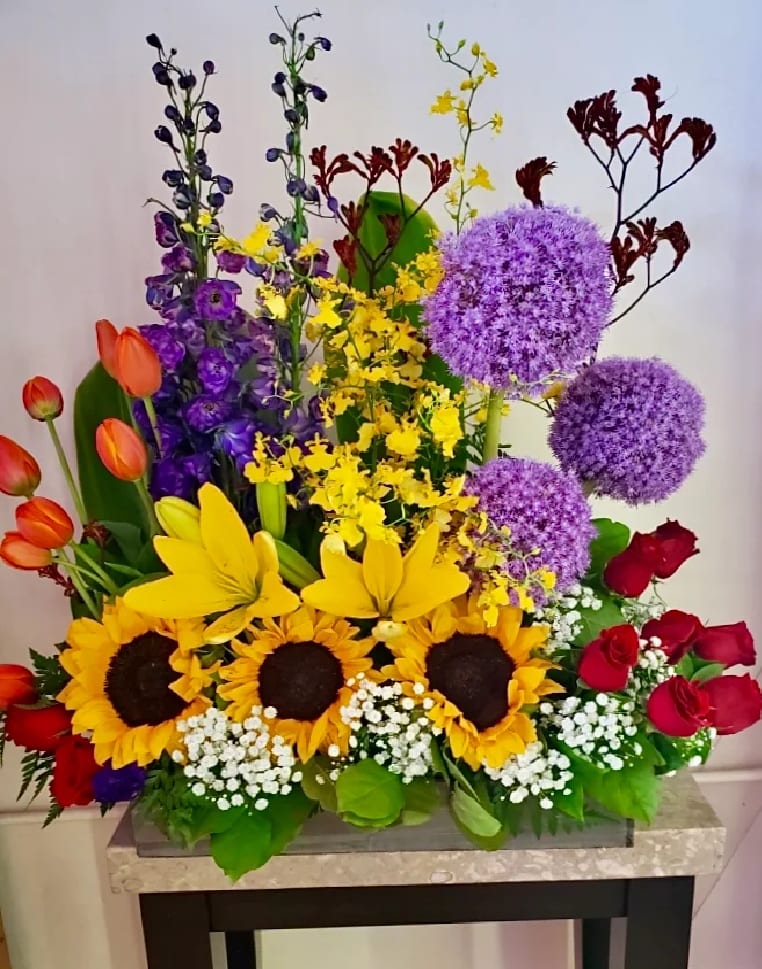 Colorful mixed flower arrangement with sunflowers, roses, tulips, and purple alliums