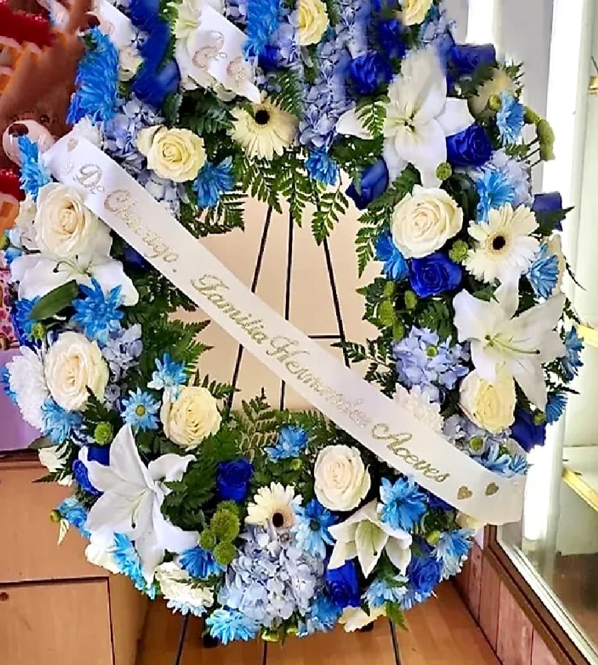 Large blue and white floral wreath with a memorial ribbon